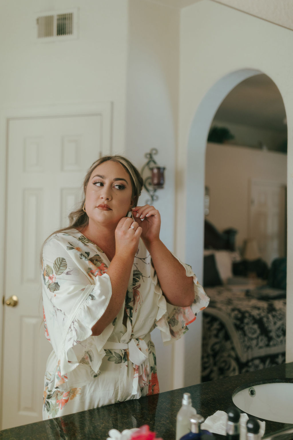 Bride putting her earring in in the mirror during wedding getting ready photos
