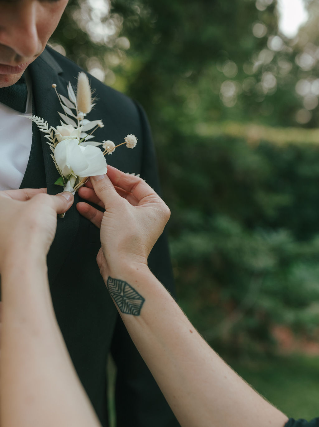 Groom having his white florals put on his lapel 