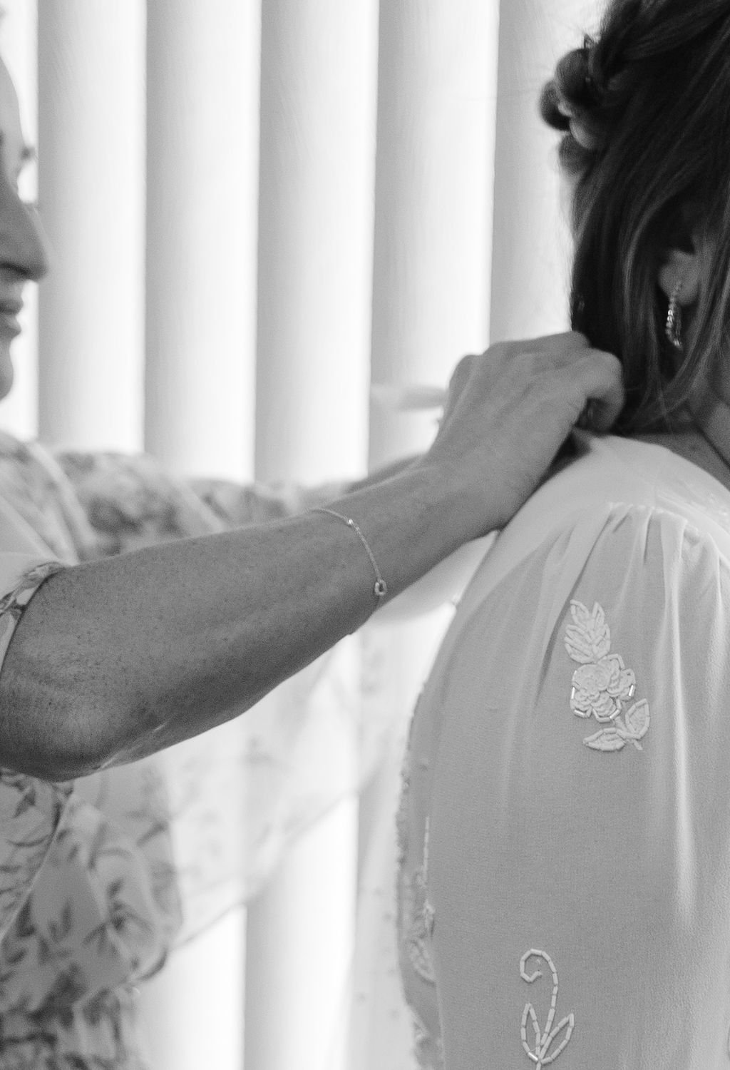 Bride's mom putting on her wedding dress during wedding getting ready photos