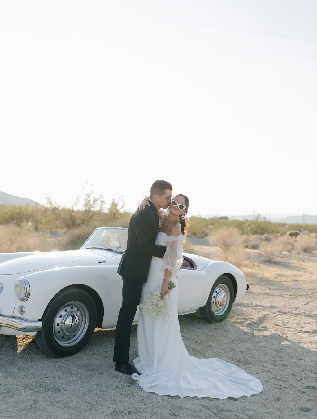 Bride and groom posing with vintage car at Joshua tree elopement