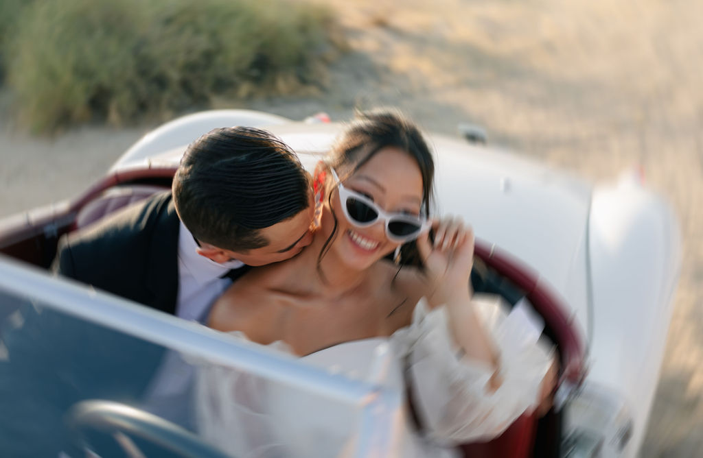 Blurry bride and groom photo of them sitting in a vintage car