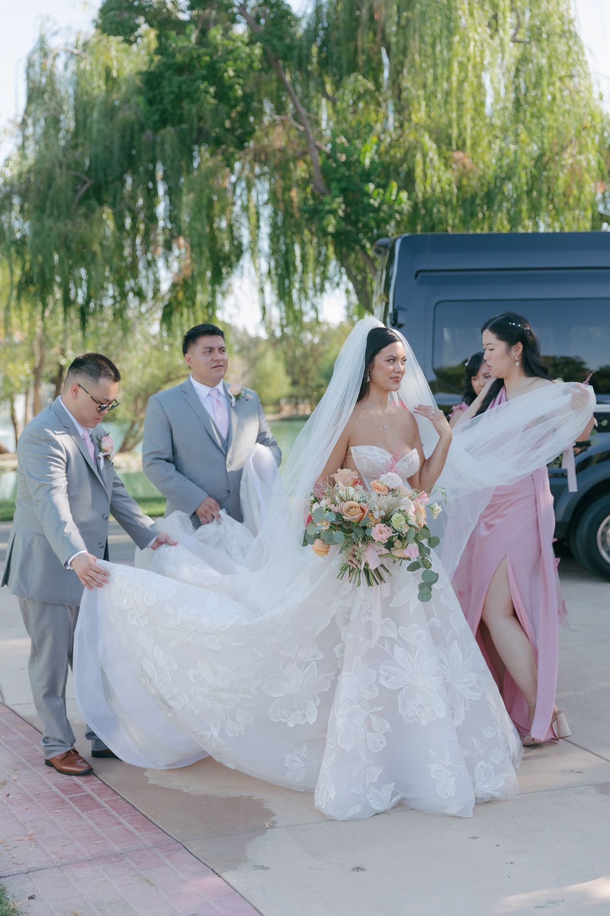 Bride preparing to walk down the aisle with bridal party fixing her veil