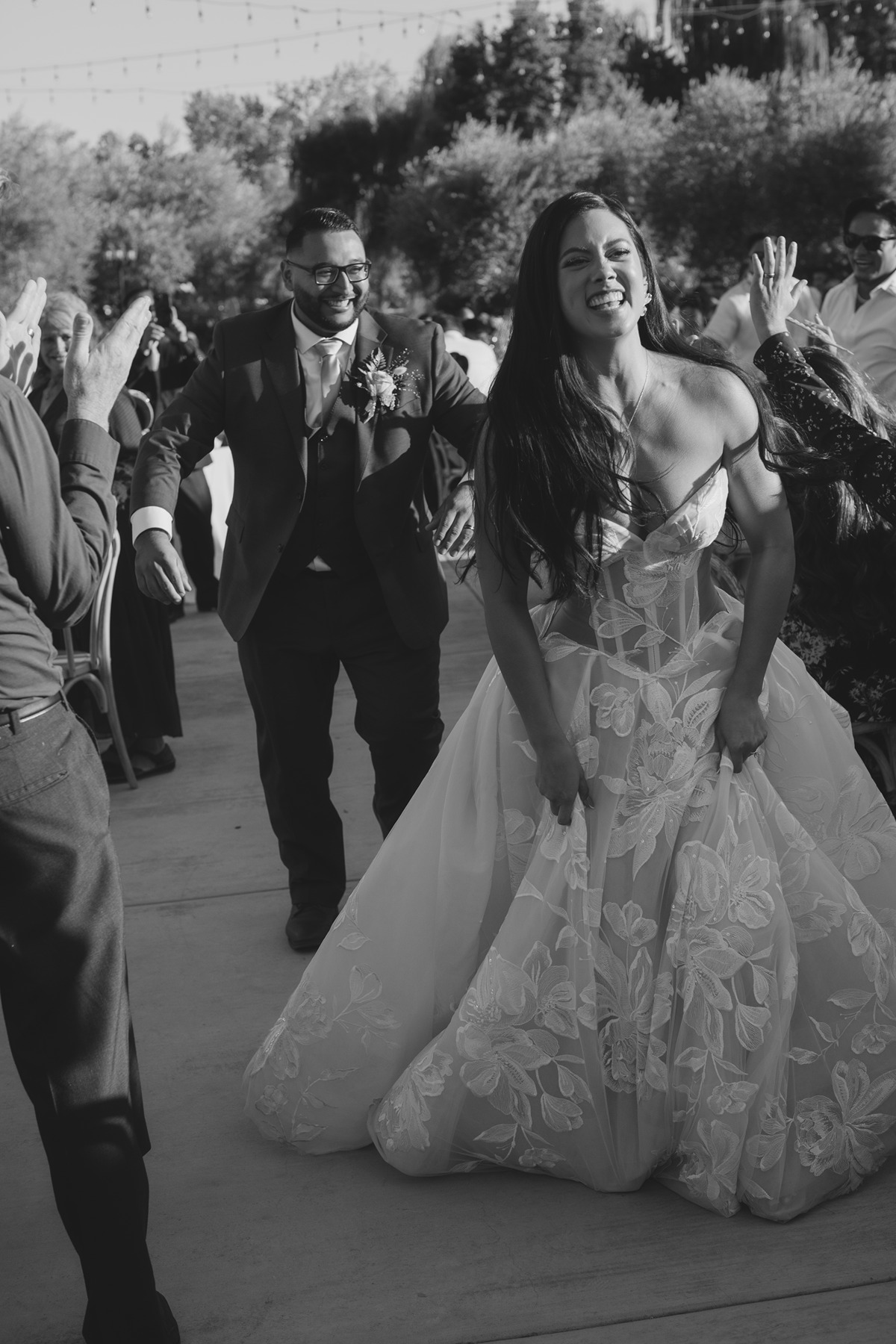 Black and white photo of bride and groom running through bridal party during bridal party photos at luxury wedding