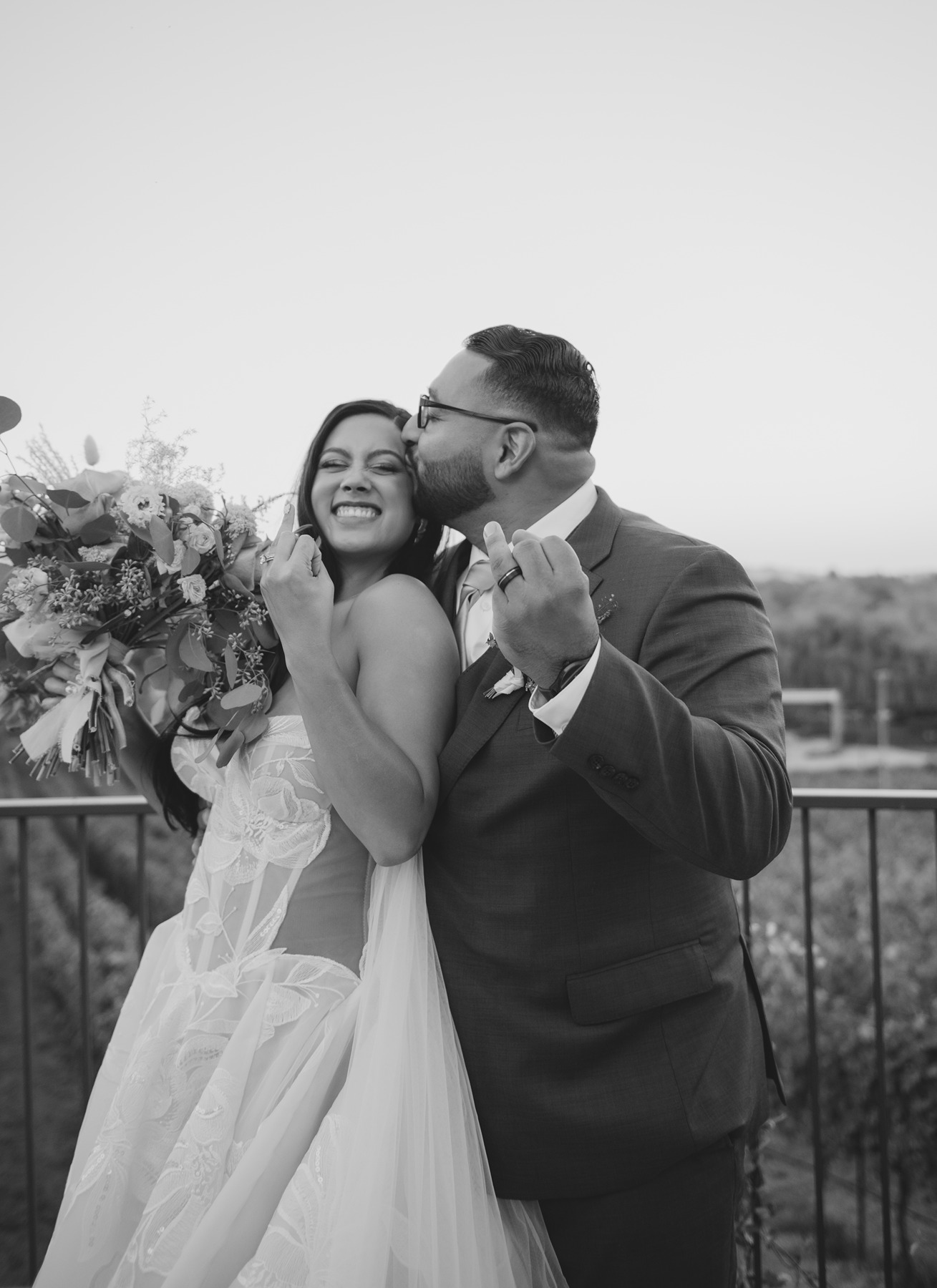 Bride and groom happily showing off their wedding rings in black and white wedding photo