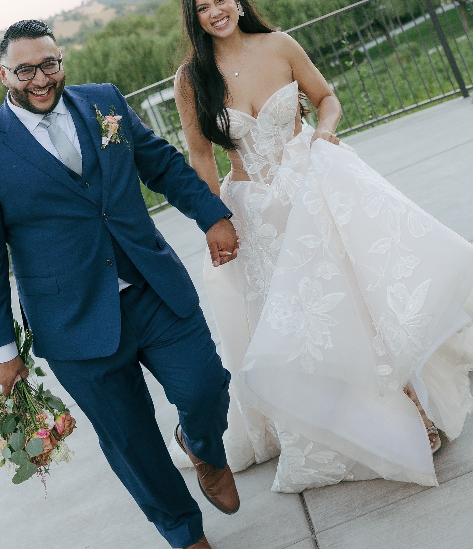 Bride and groom happily walking towards the camera laughing in editorial wedding photo