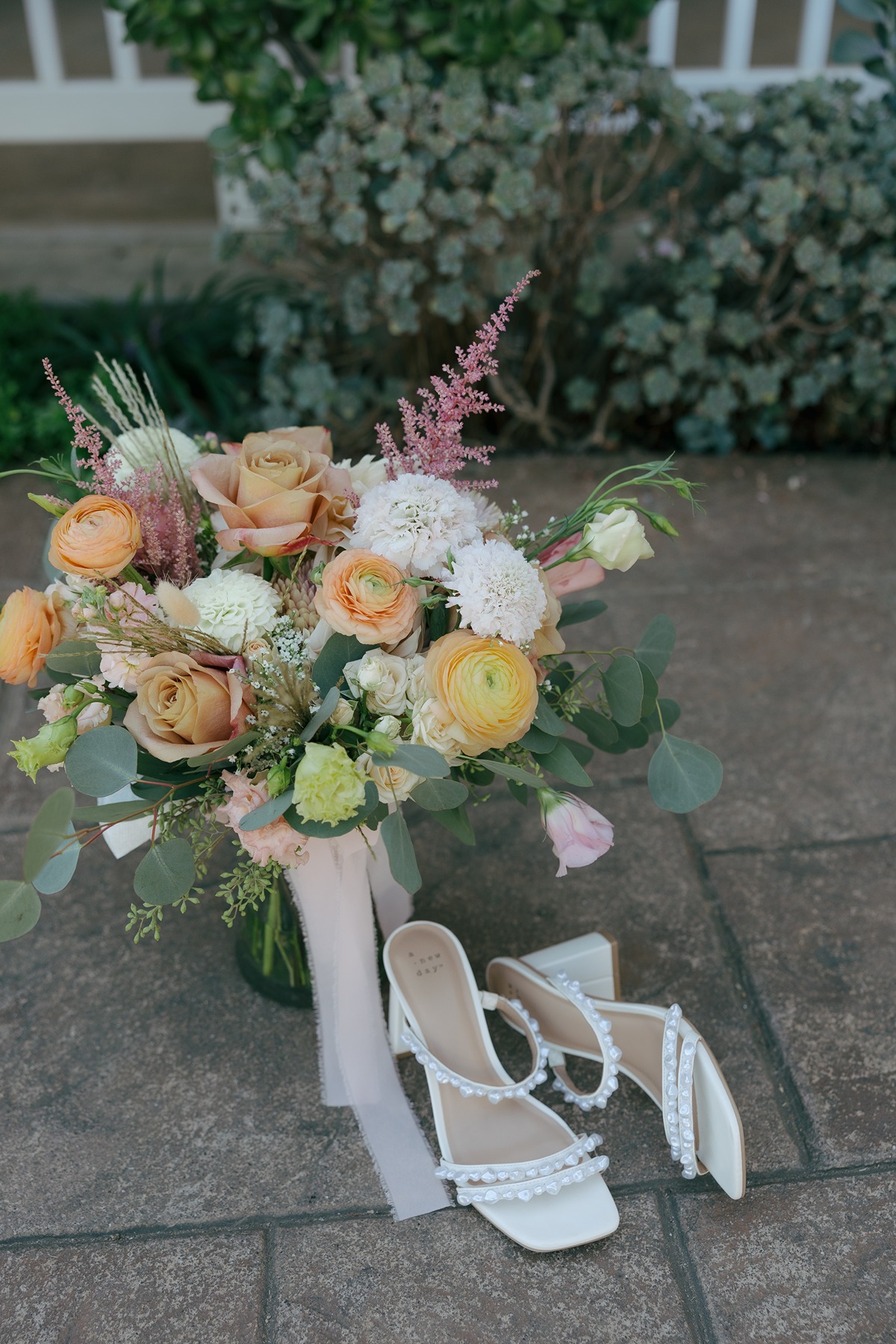 Wedding detail photo of pearl wedding shoes and wildflower wedding bouquet