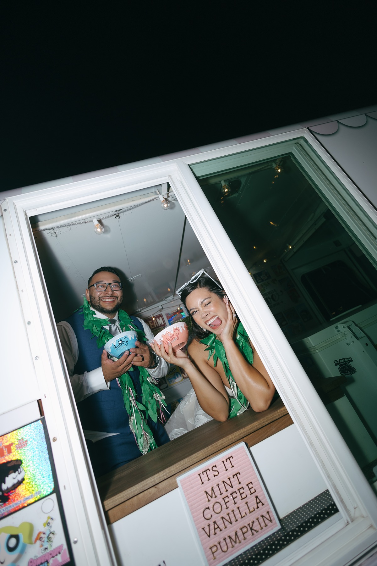Bride and groom in an ice cream truck after their wedding making silly poses