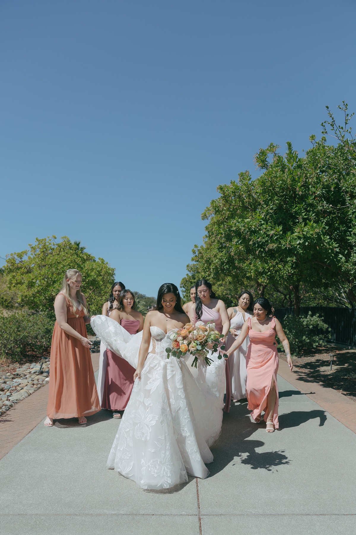 Bridesmaids holding brides wedding dress train in bridal party photos