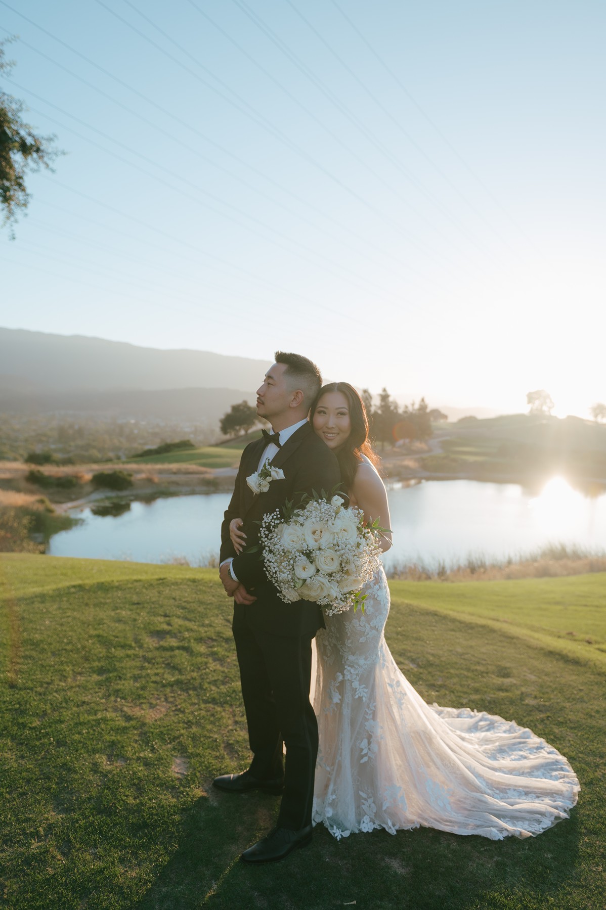 Bride and groom portraits on a golf course wedding venue with a pond behind them