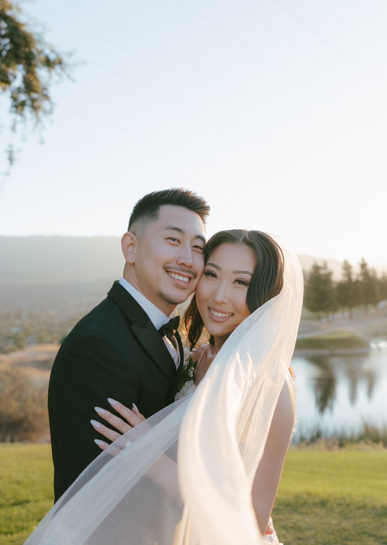 Bride and groom posing for portraits with statement veil wrapped around them