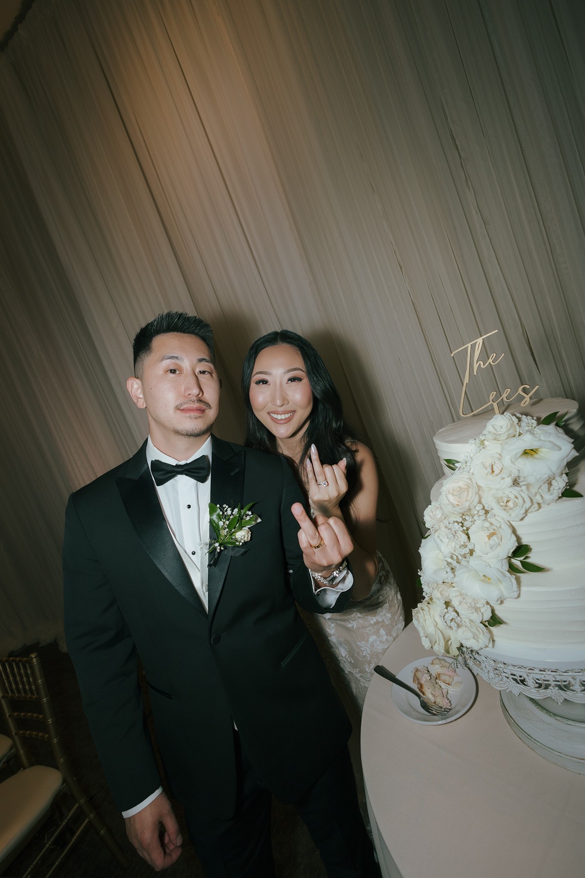 Bride and groom showing off their wedding rings during cake cutting