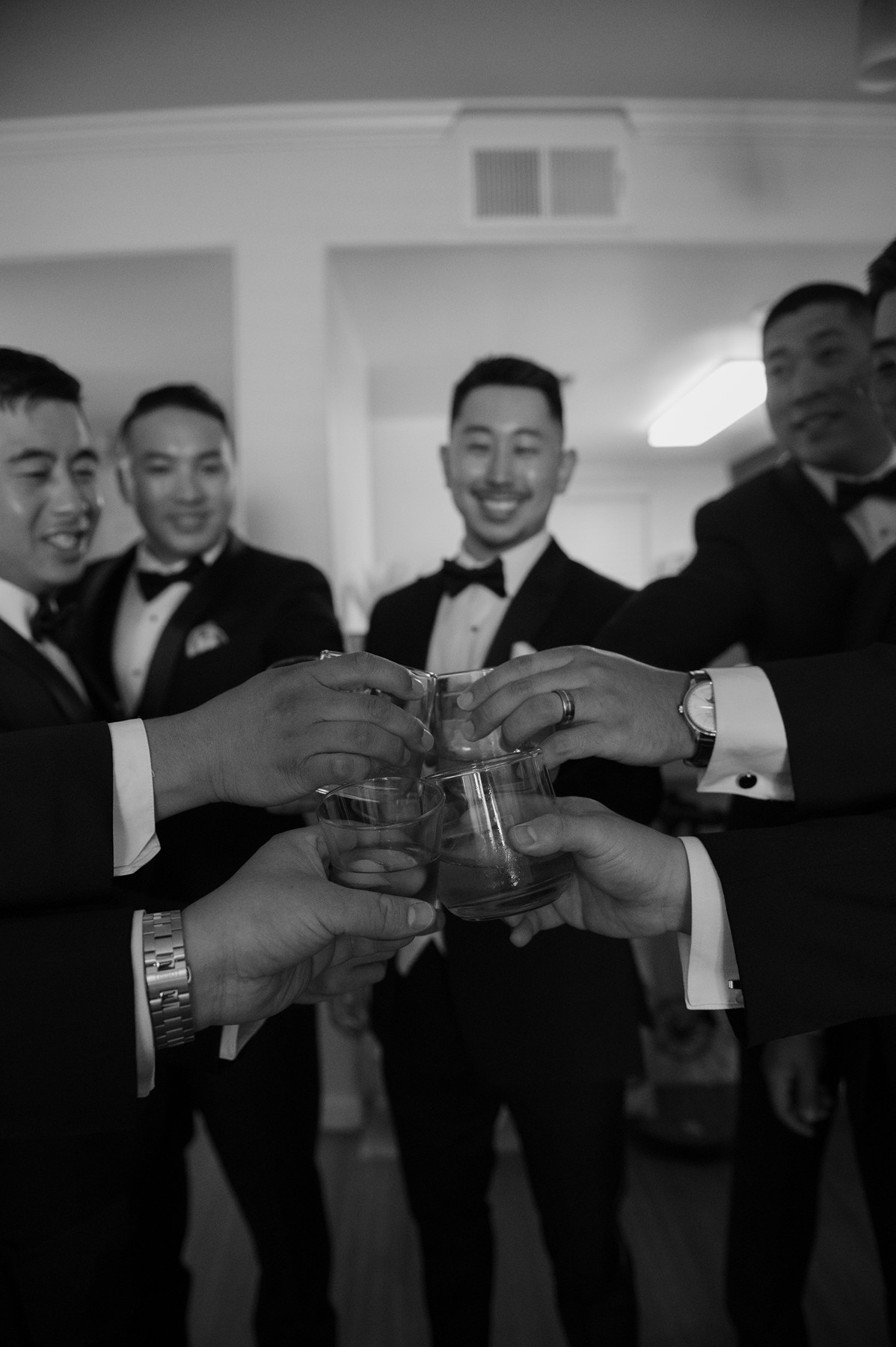 Groomsmen clinking whiskey glasses together during wedding getting ready photos
