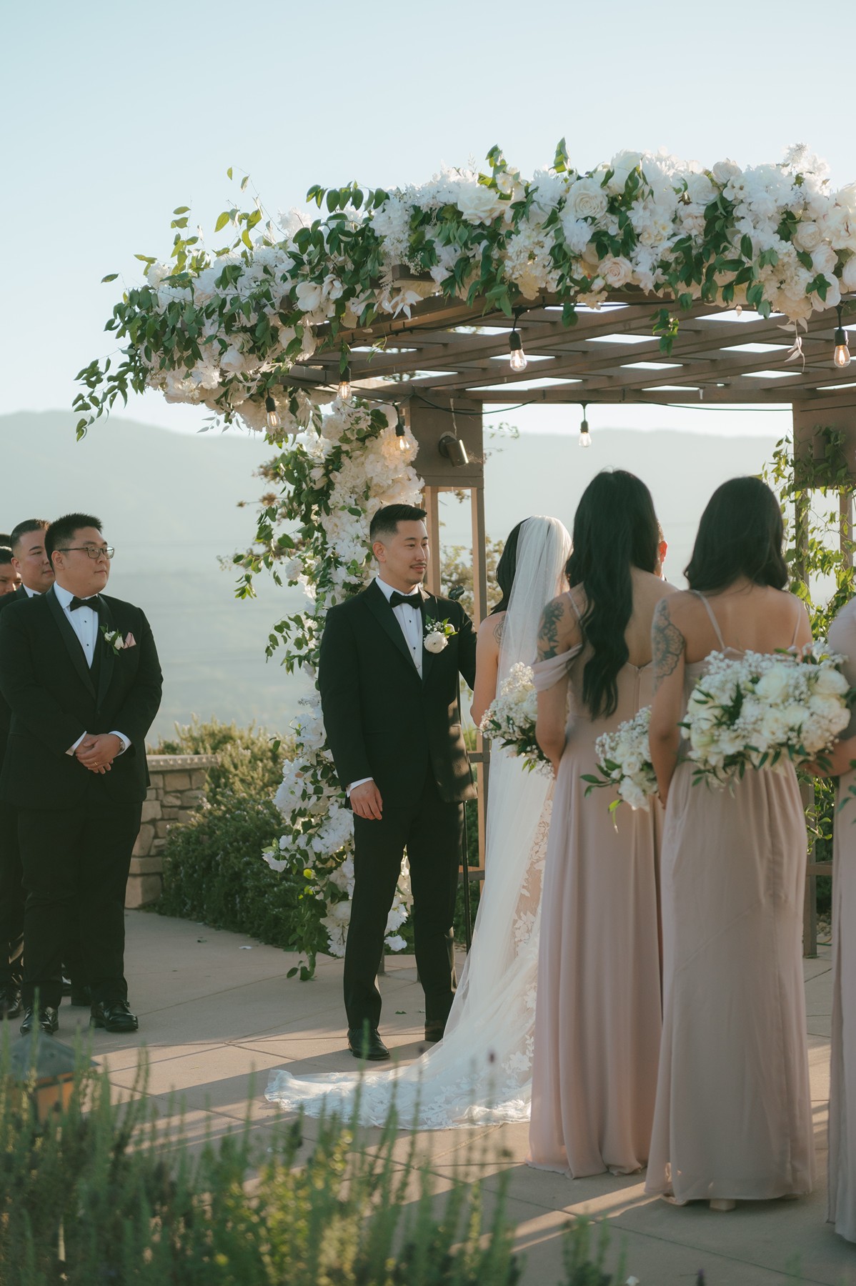Wedding ceremony with white floral details and blush bridesmaid dresses