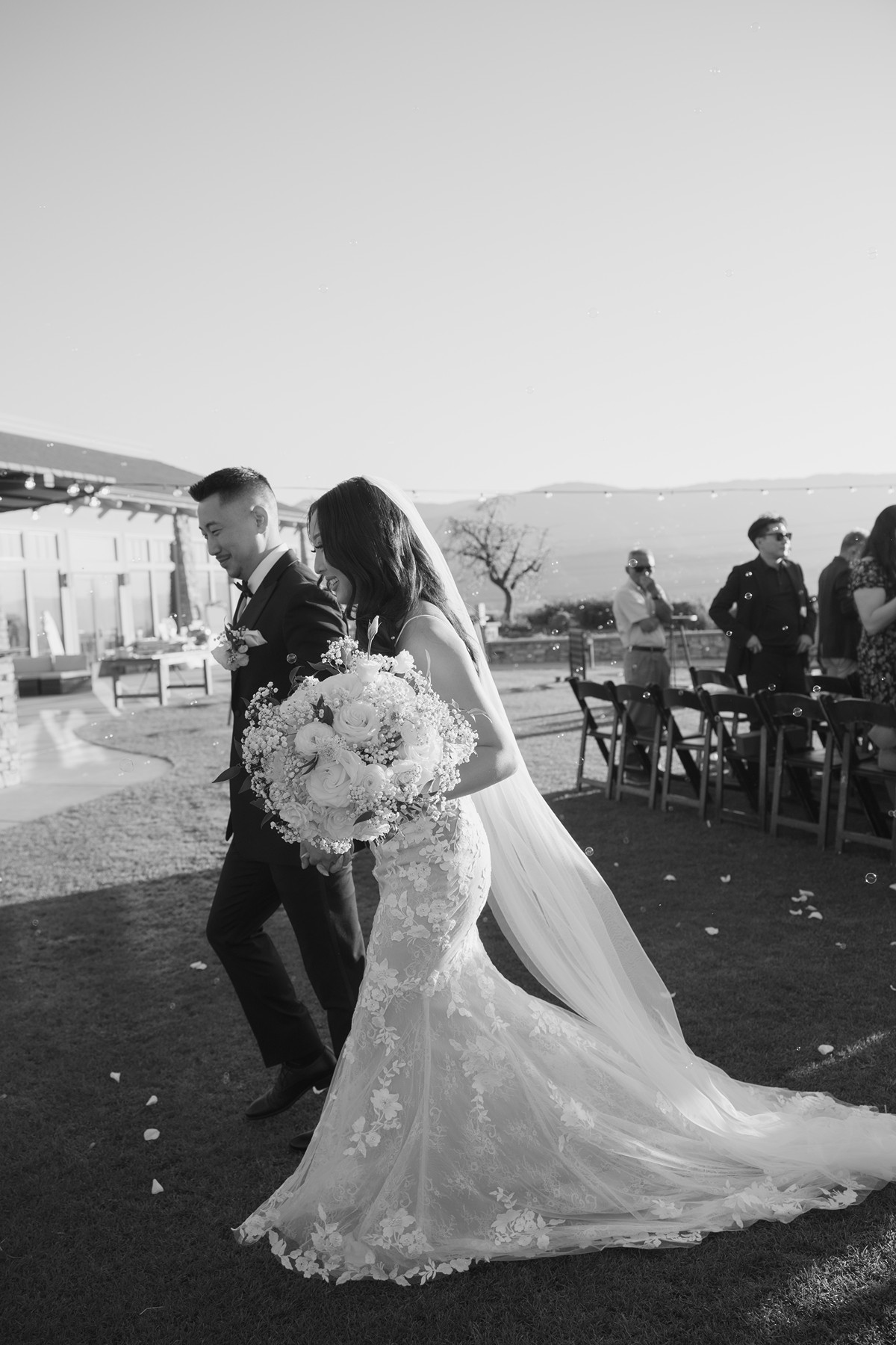 Black and white photo of bride and groom walking away from their wedding ceremony