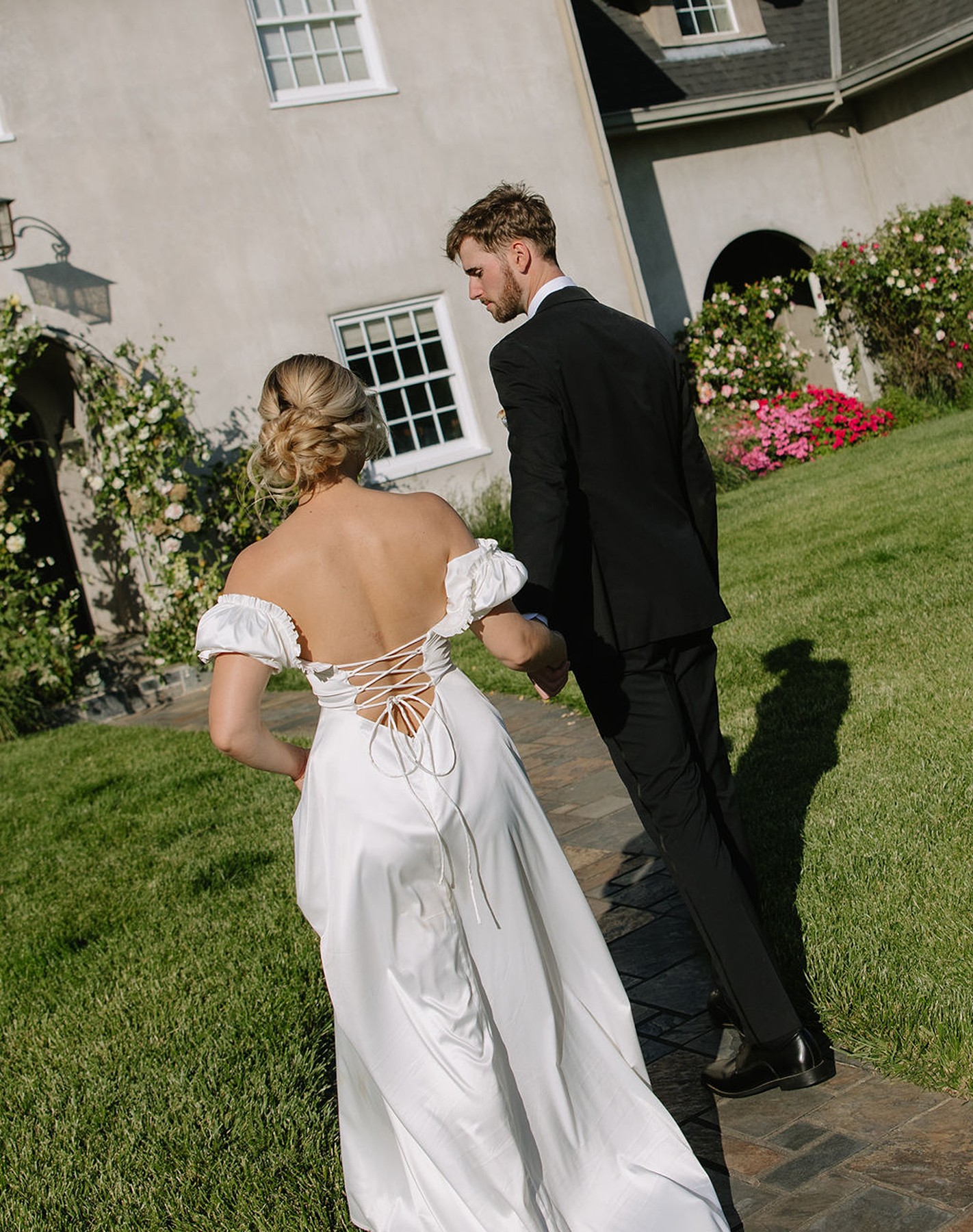 Bride and groom walking towards European wedding venue with bride in a corset back dress