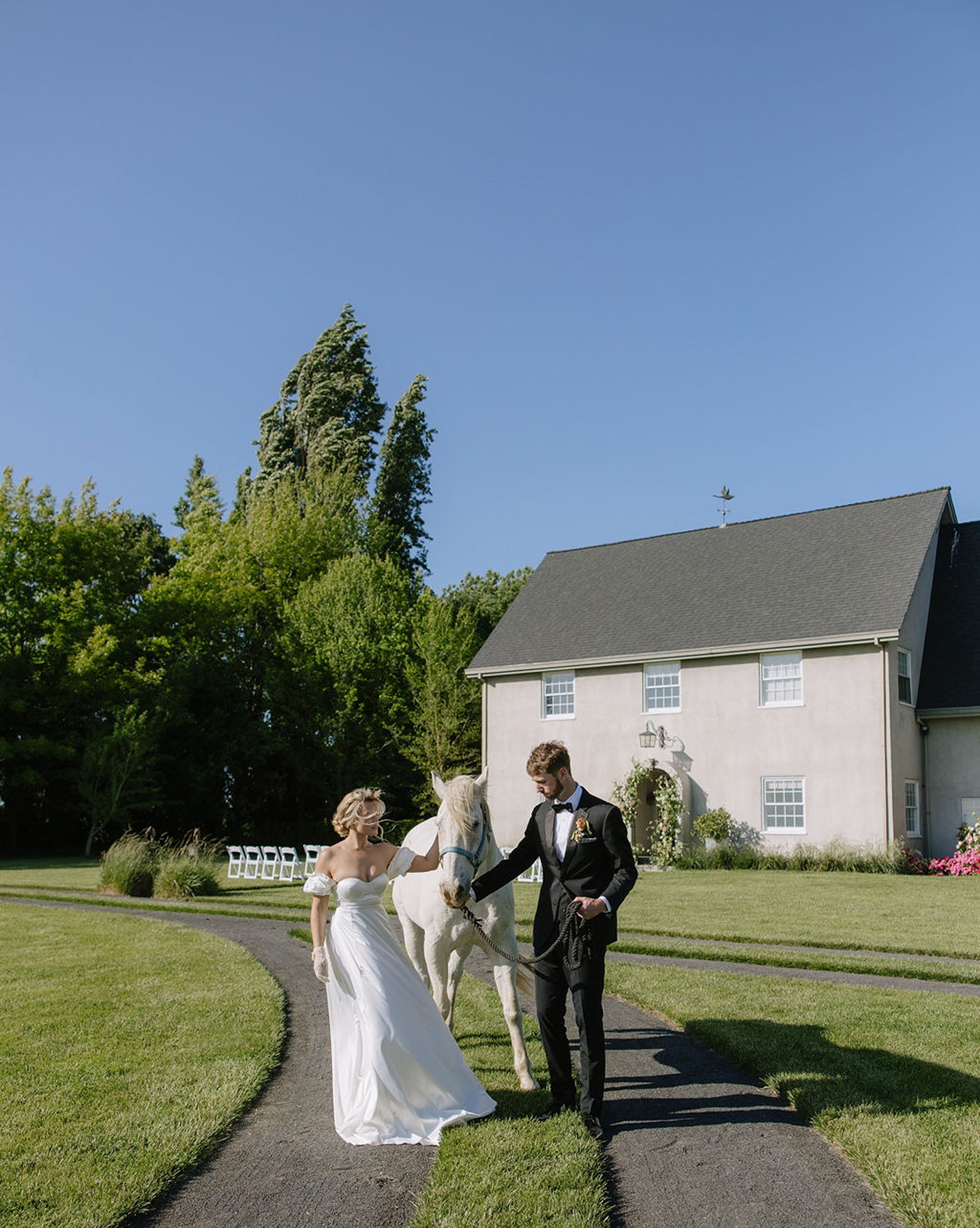 Couple standing in front of a country estate petting a horse for wedding photos