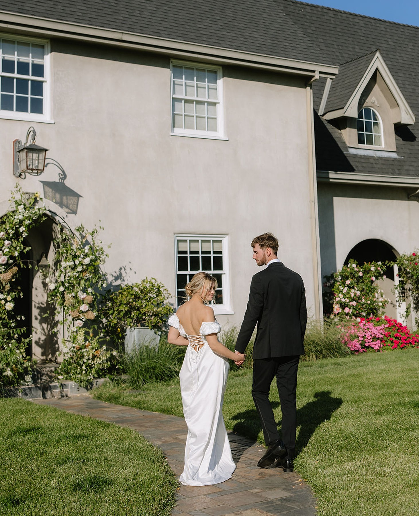 Bride and groom holding hands in front of estate wedding venue