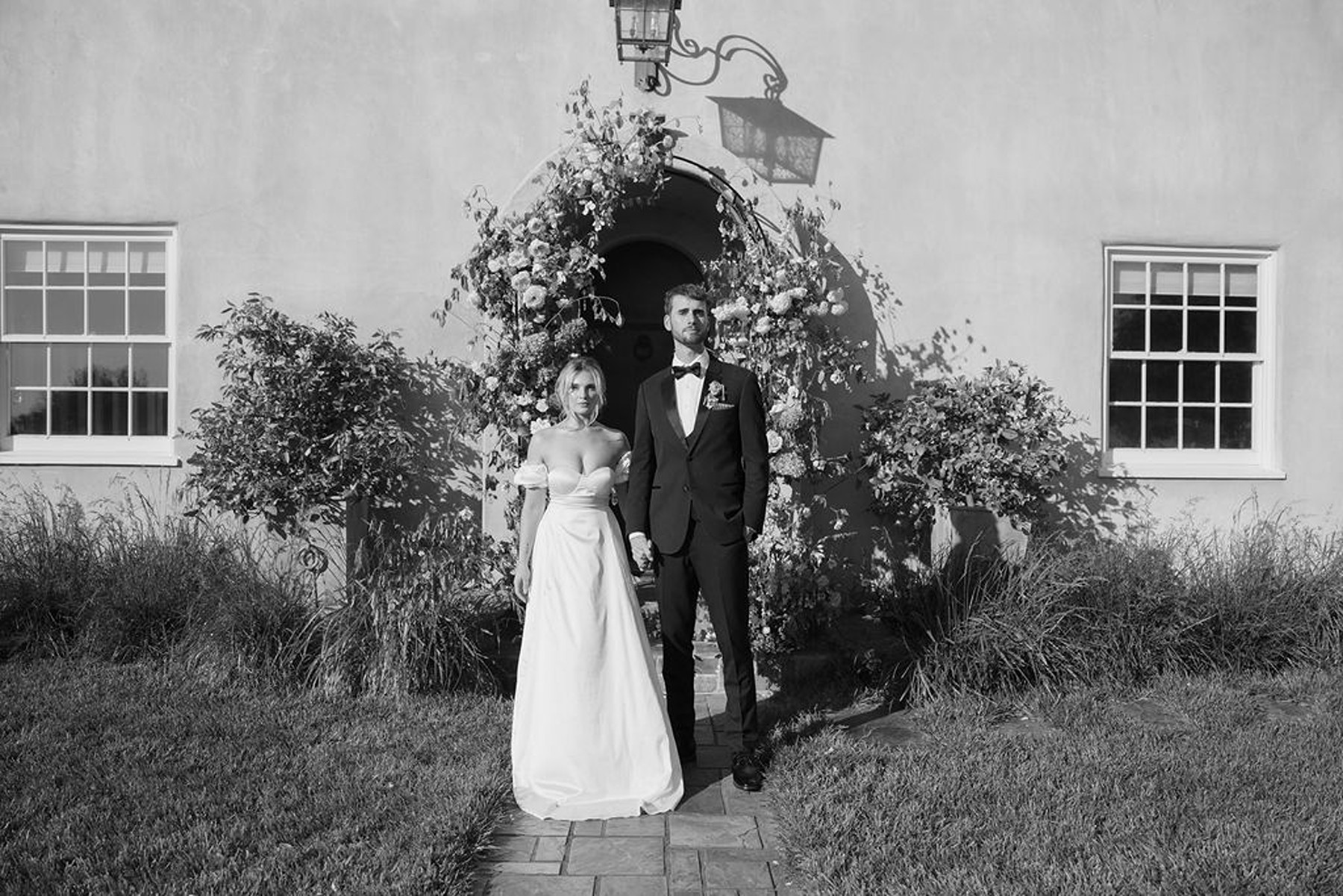 Black and white wedding photo of couple holding hands in front of ceremony site at Cavaignac, a country estate
