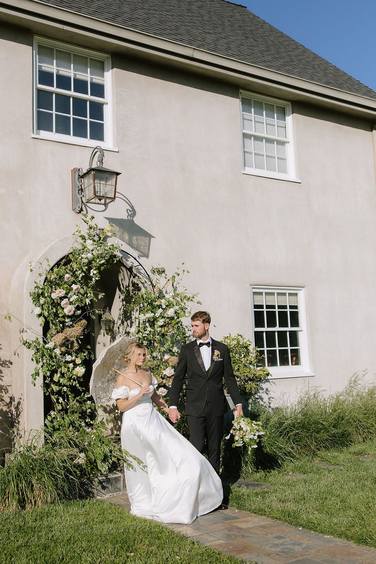 Bride and groom walking away from their ceremony site with bride holding a parasol