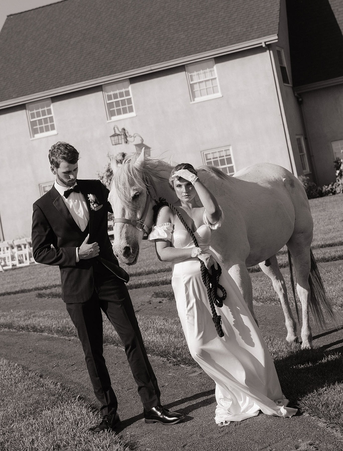 Black and white editorial photo of couple posing with a horse in front of Italian wedding venue