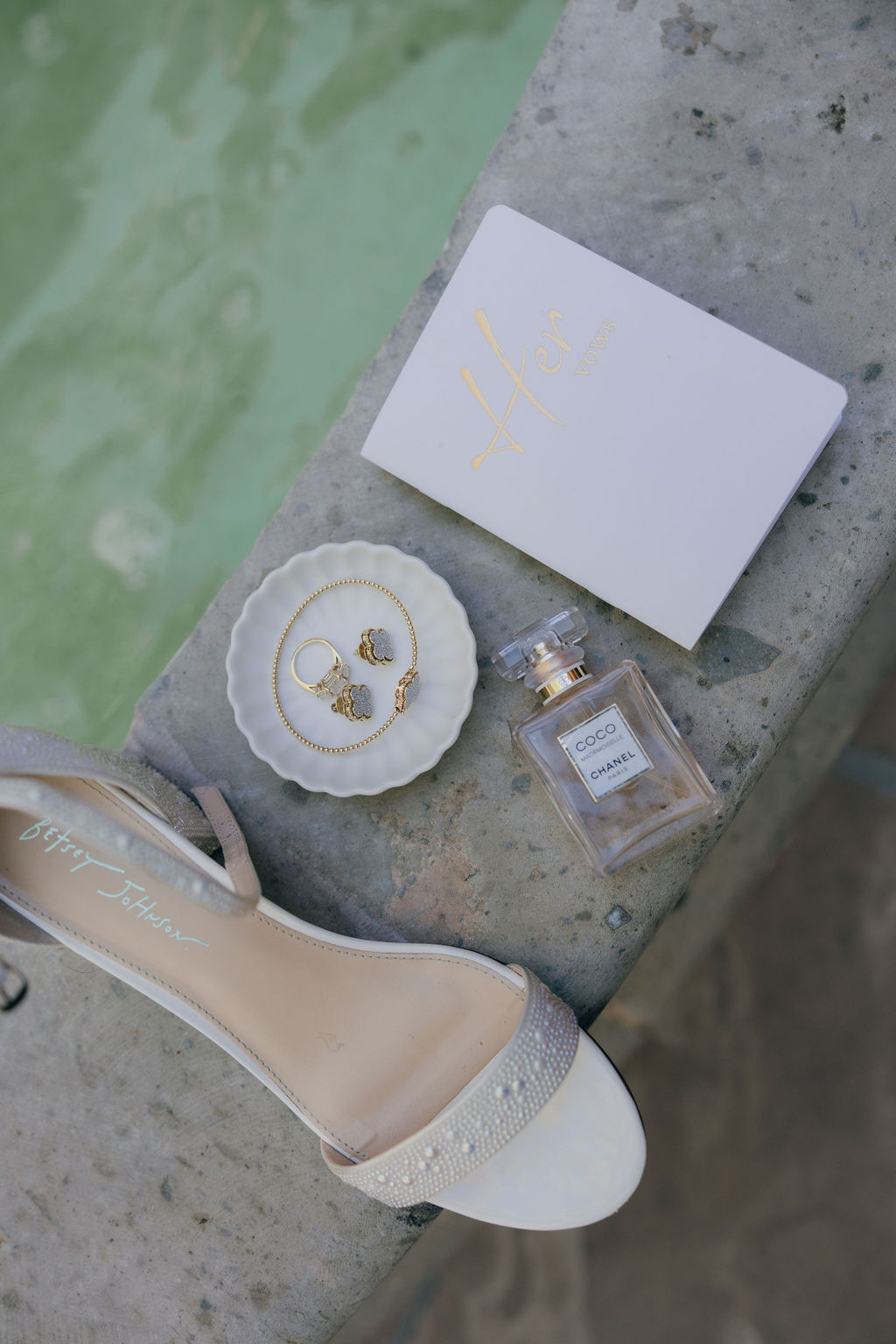 Wedding details, including the bride's shoes and wedding jewelry by the fountain