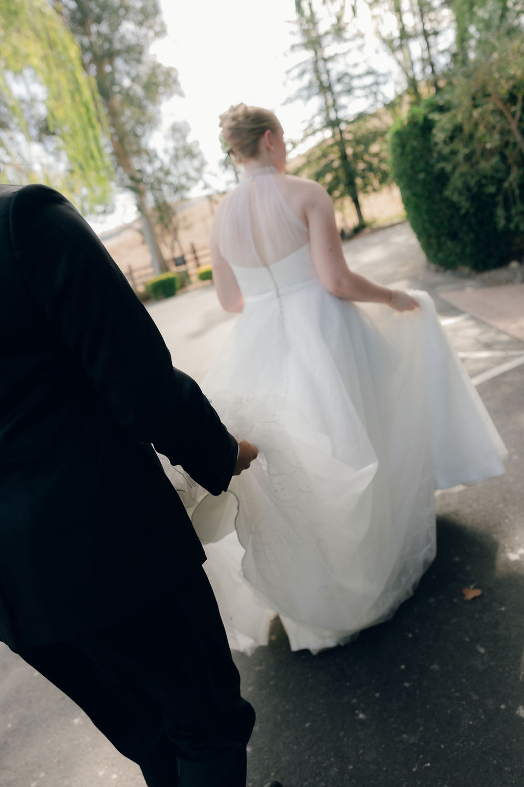 Groom carrying the bride's wedding dress train in a documentary wedding photo