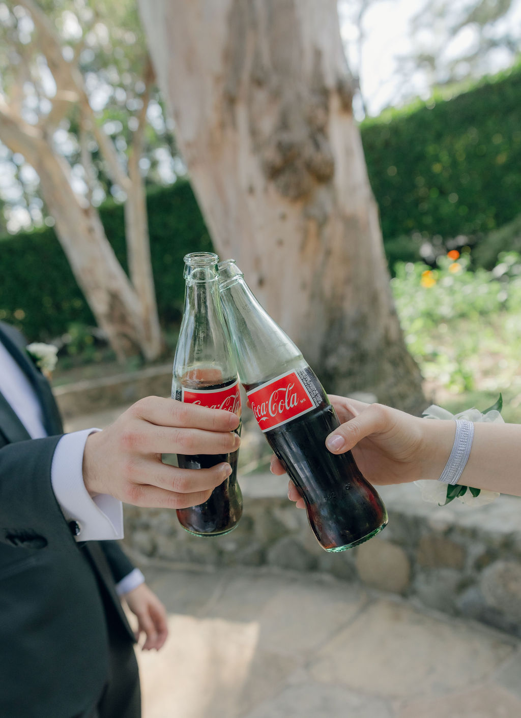 Candid wedding photo of wedding guests clanking glass coke bottles