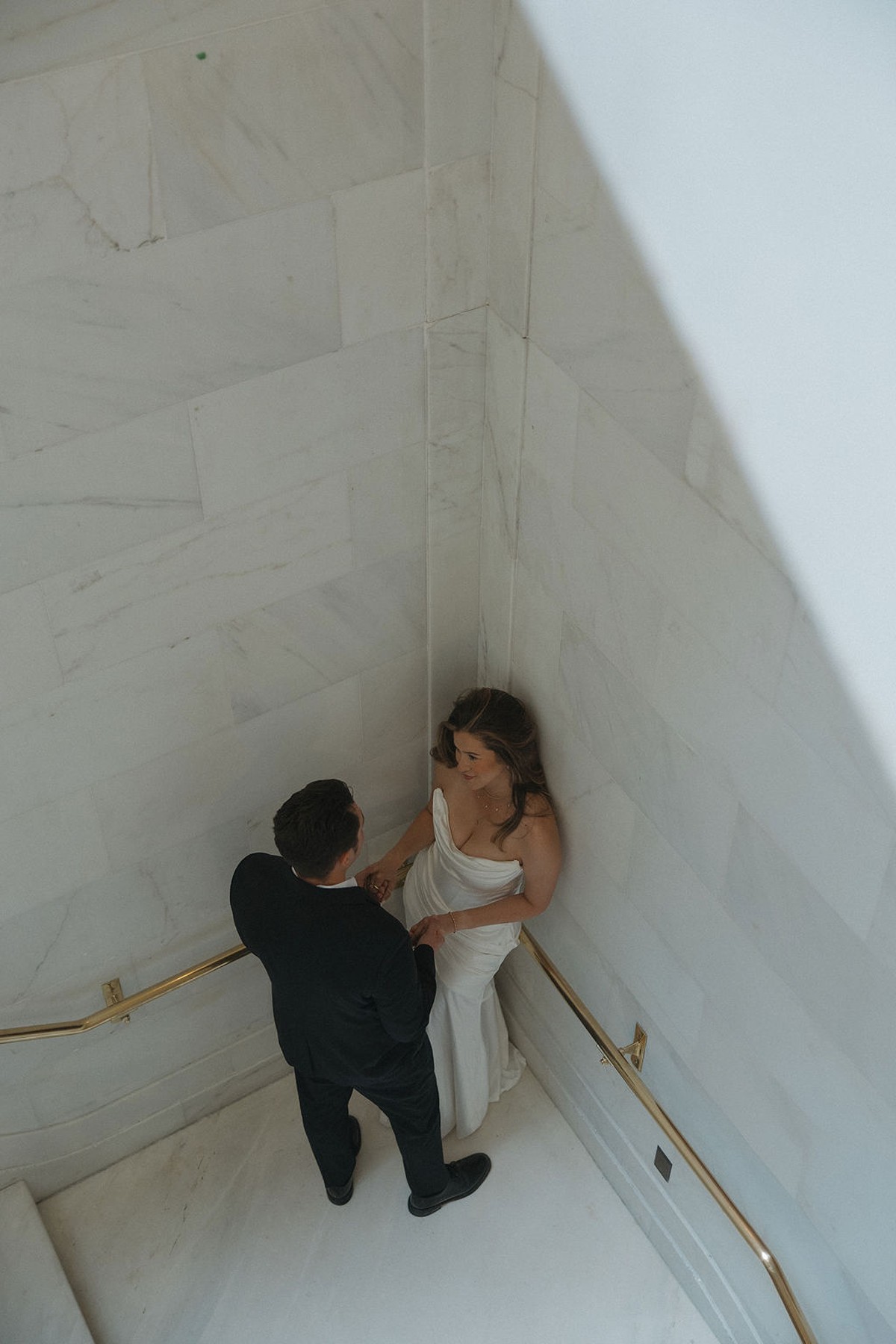 Arial photo of the couple in a corner on the marble staircase at San Francisco city hall