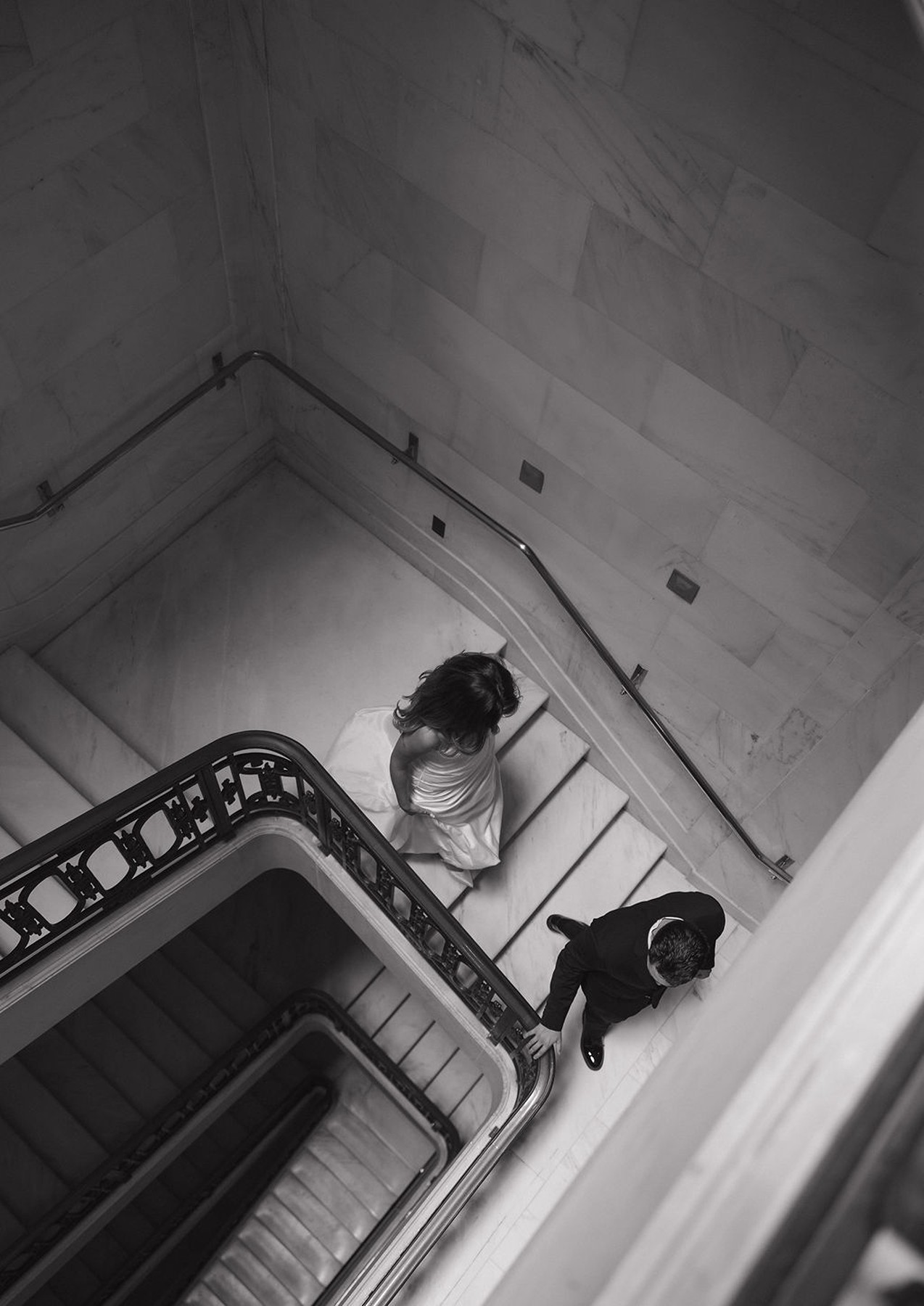Black and white photo of couple walking down a marble staircase