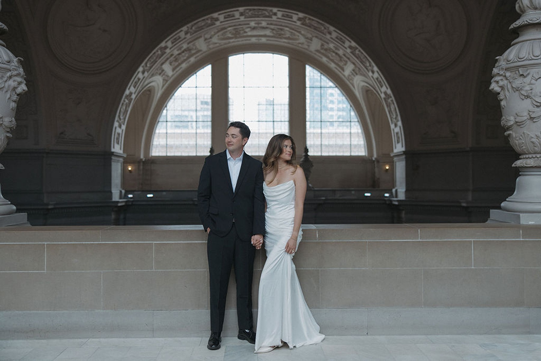 Couple standing in front of iconic San Francisco City Hall window facing opposite directions