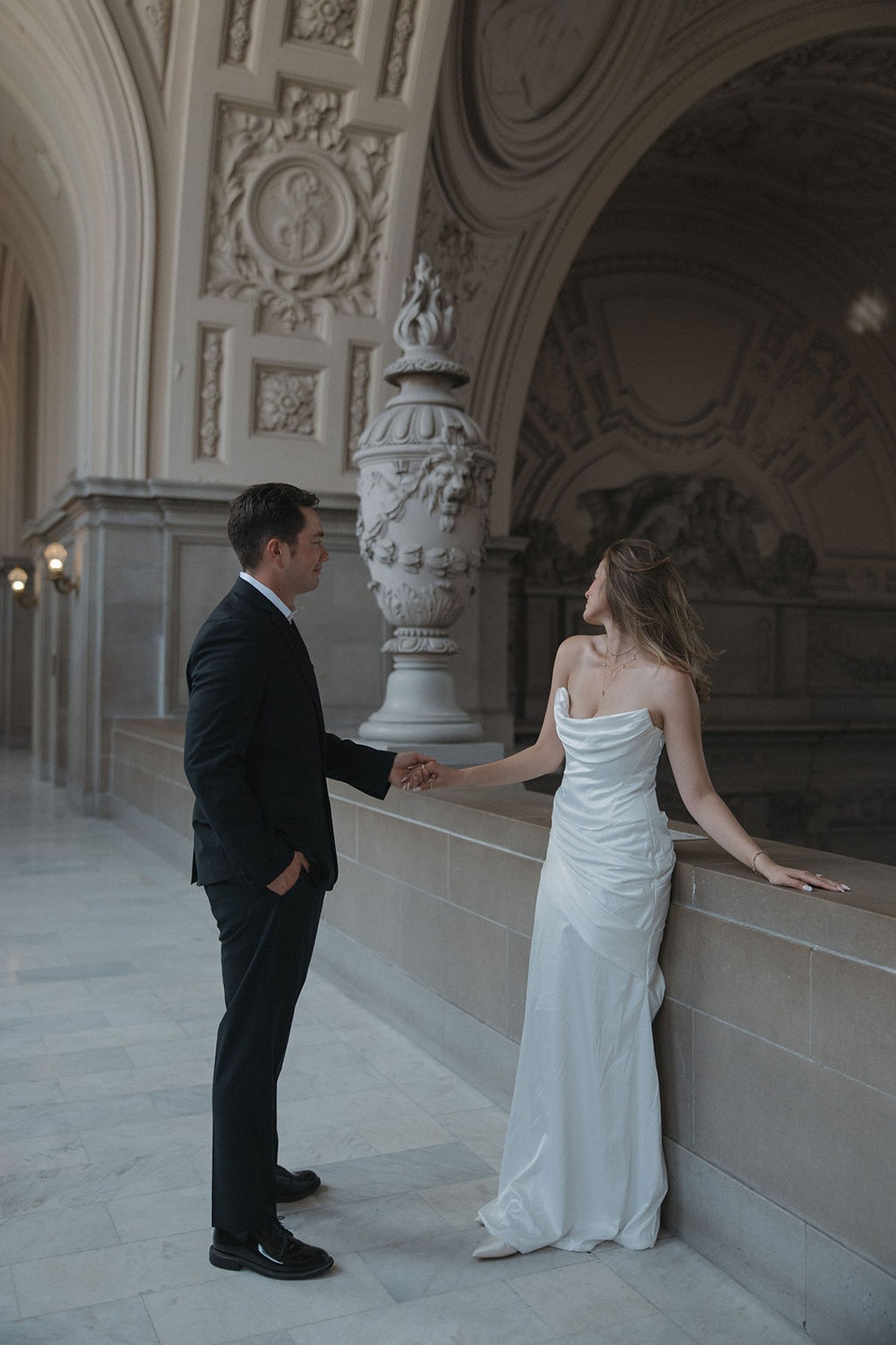 Bride and groom posing for photos in a hallway at San Francisco city hall wedding