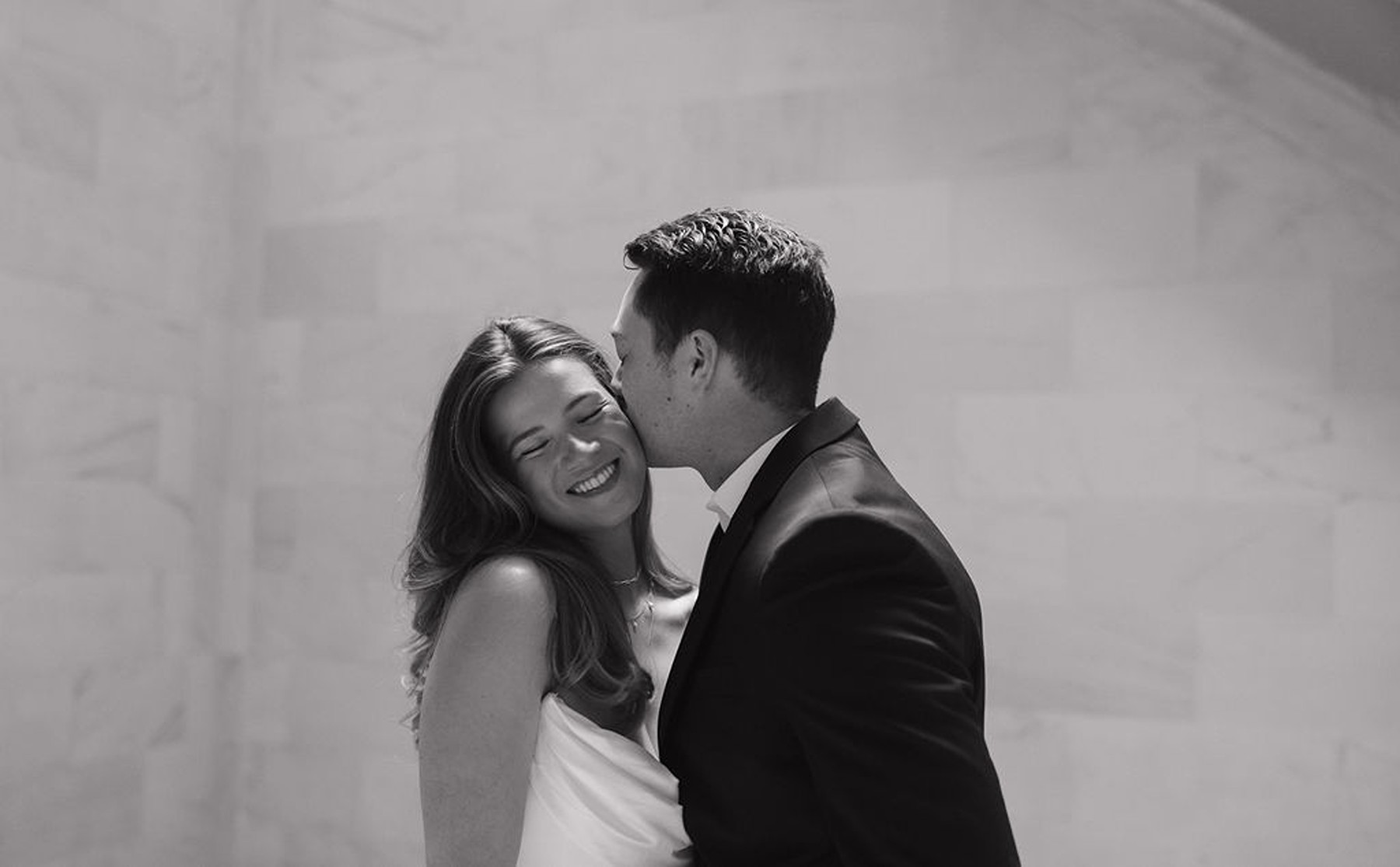 Groom kissing bride on the cheek and her smiling in wedding photo