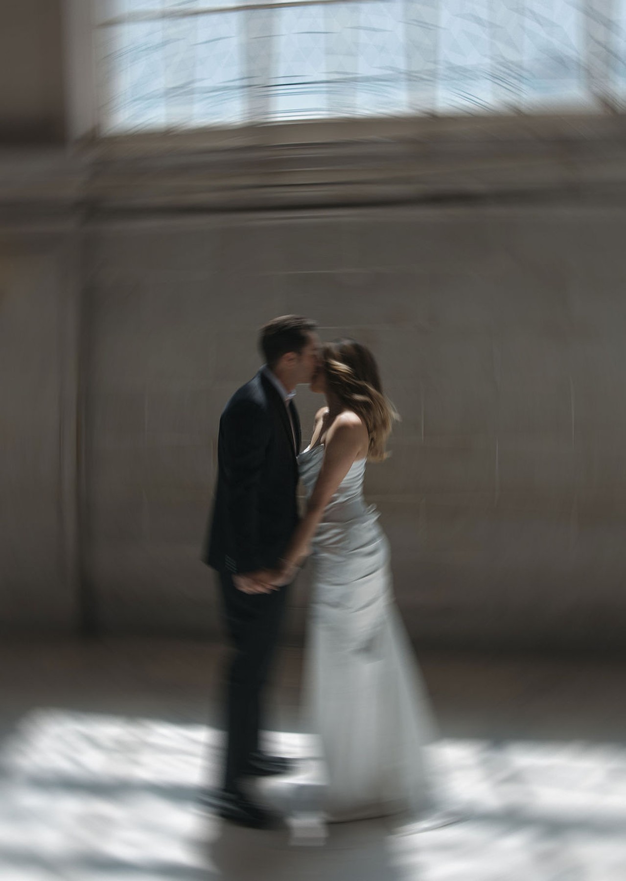 Blurry city hall wedding photo of groom kissing bride's forehead