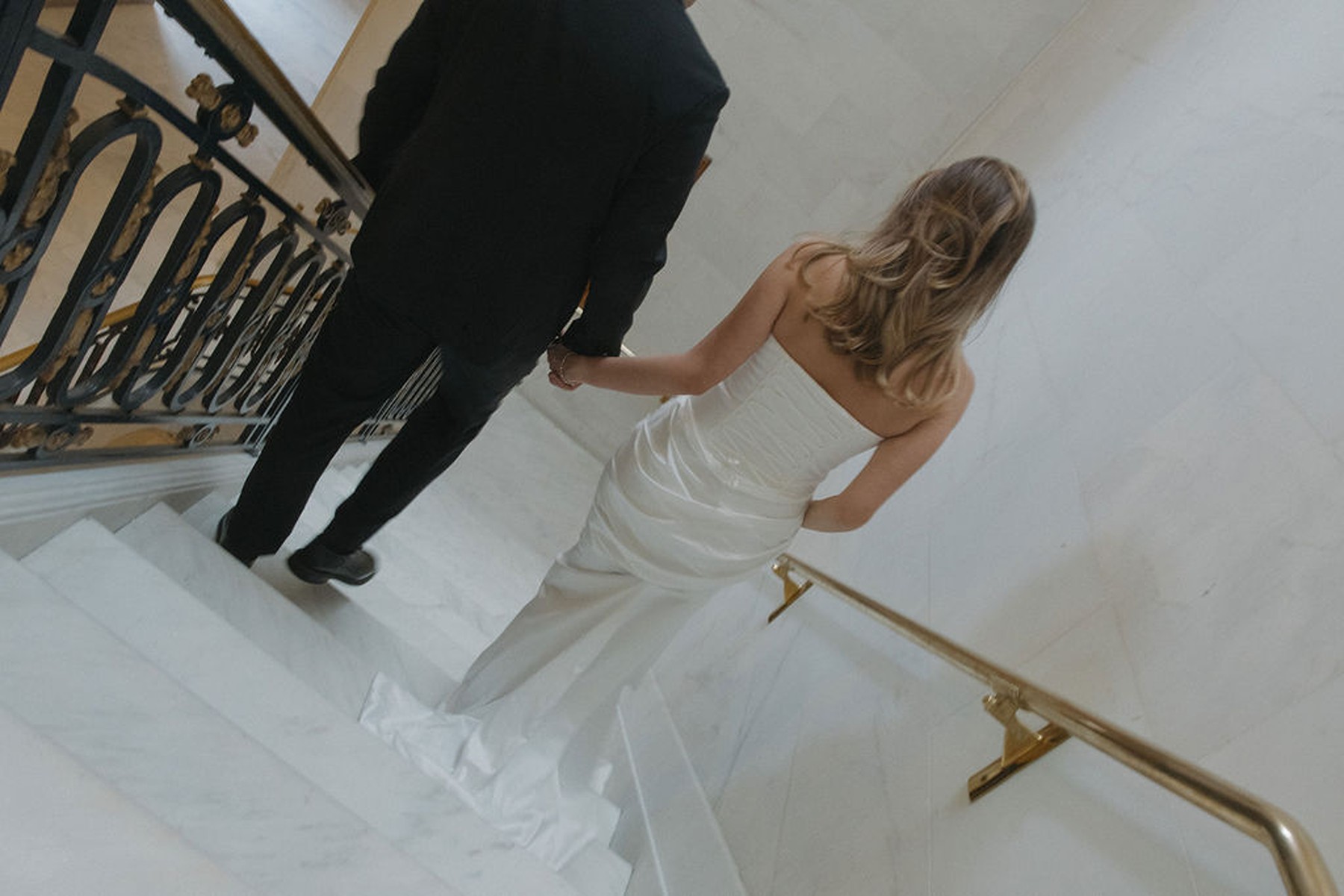 Blurry editorial wedding photo of bride walking down marble staircase at San Francisco city hall