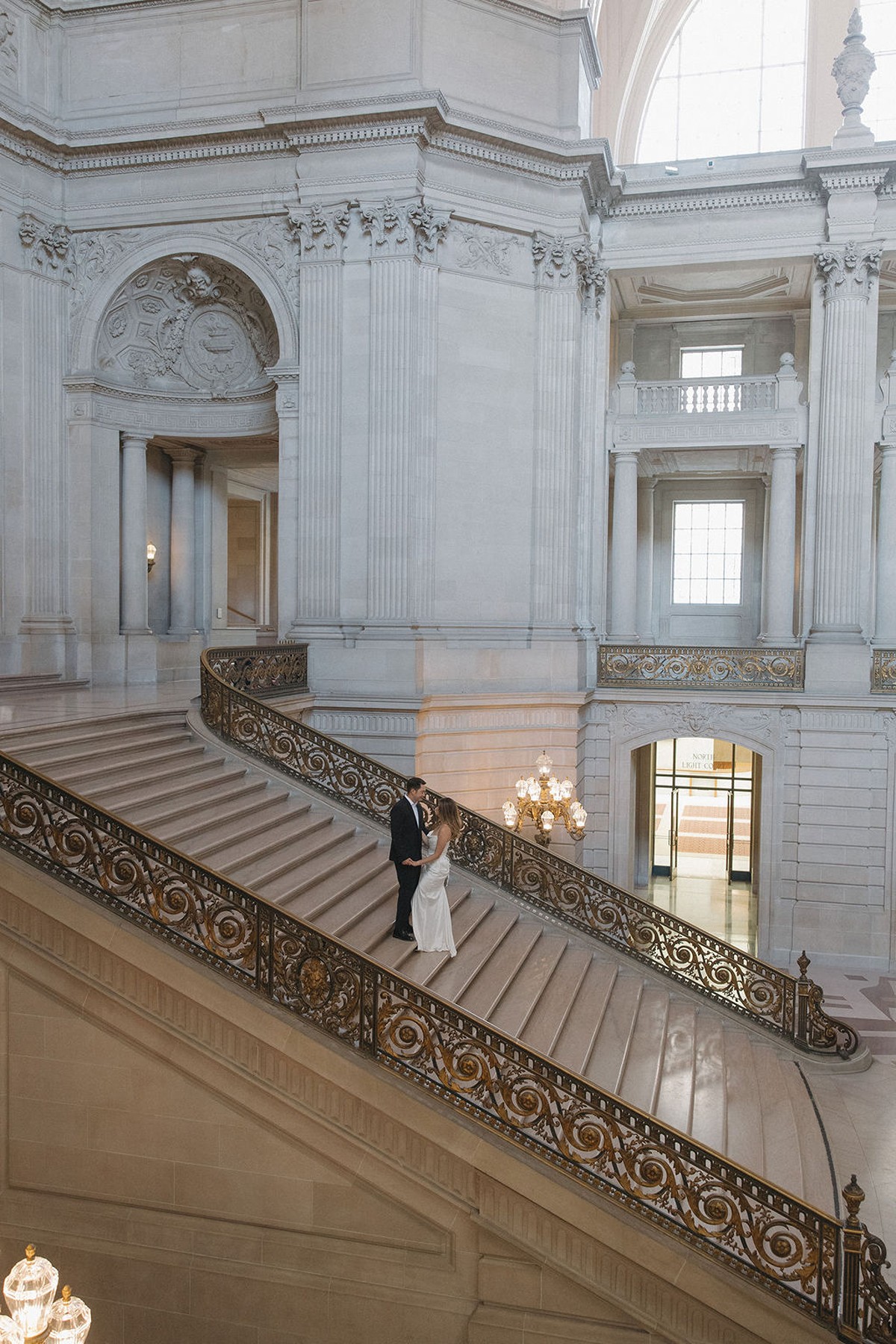 Couple posing for wedding photos on the grand staircase at San Francisco city hall