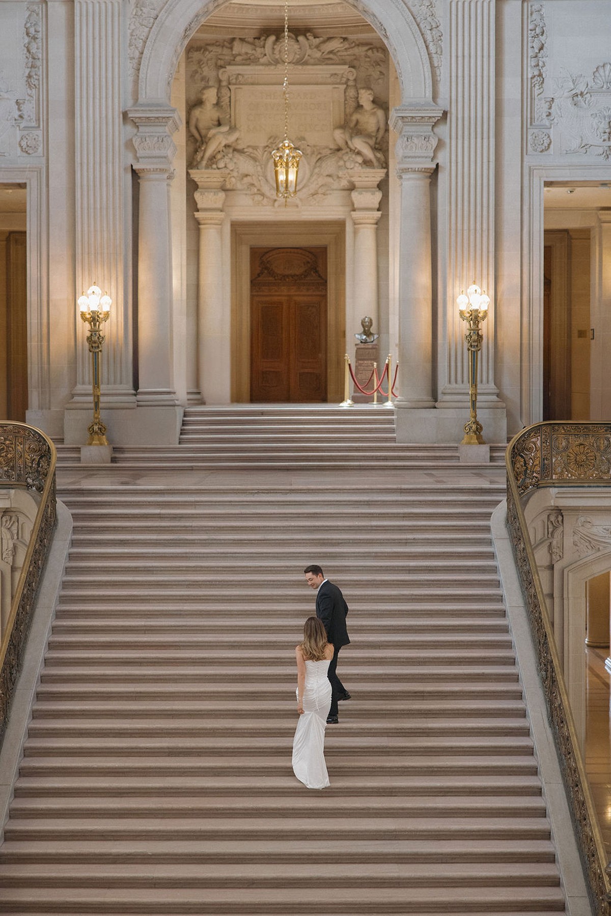Couple walking up the grand staircase at San Francisco city hall wedding