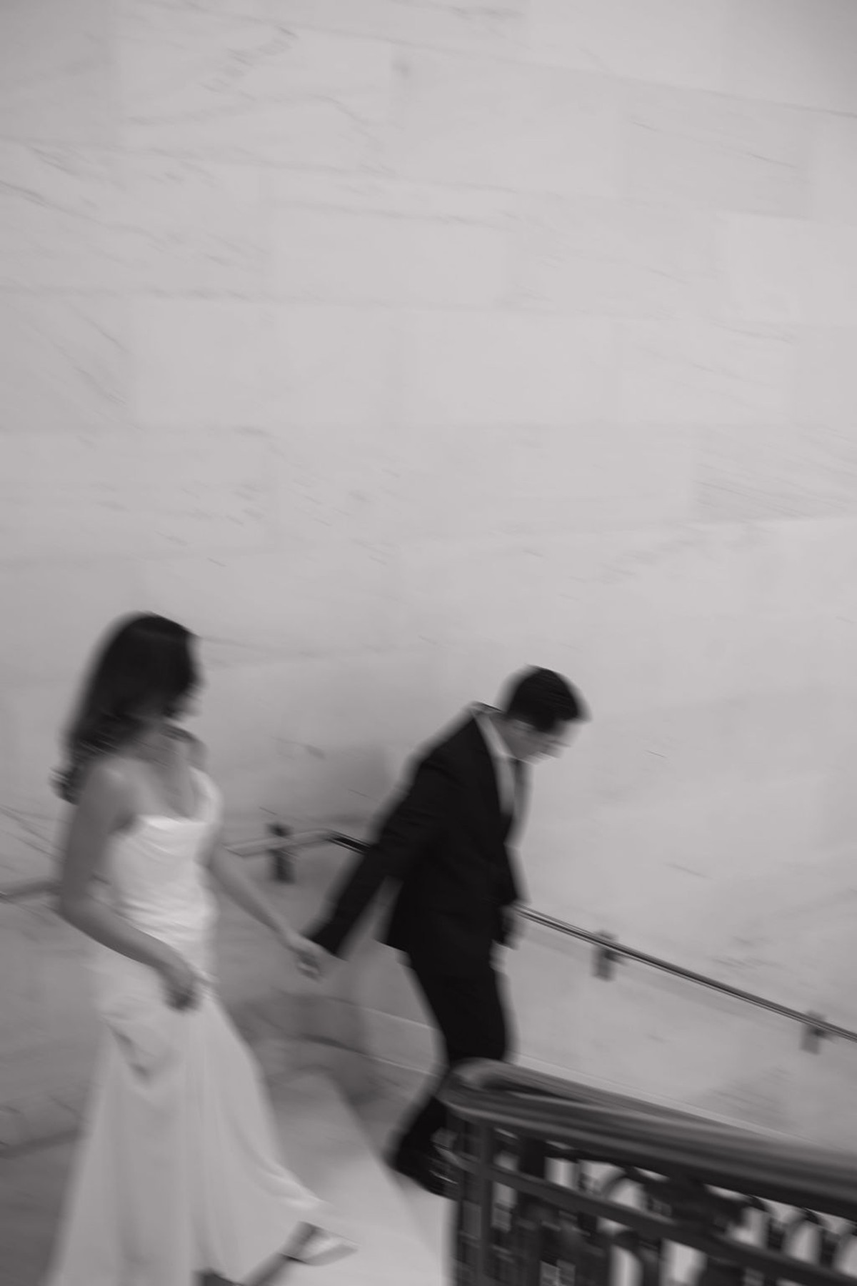 Black and white blurry photo of couple walking down the marble staircase at San Francisco city hall