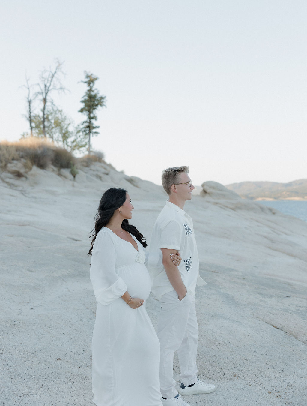 Couple looking out at the lake while woman holds her baby bump