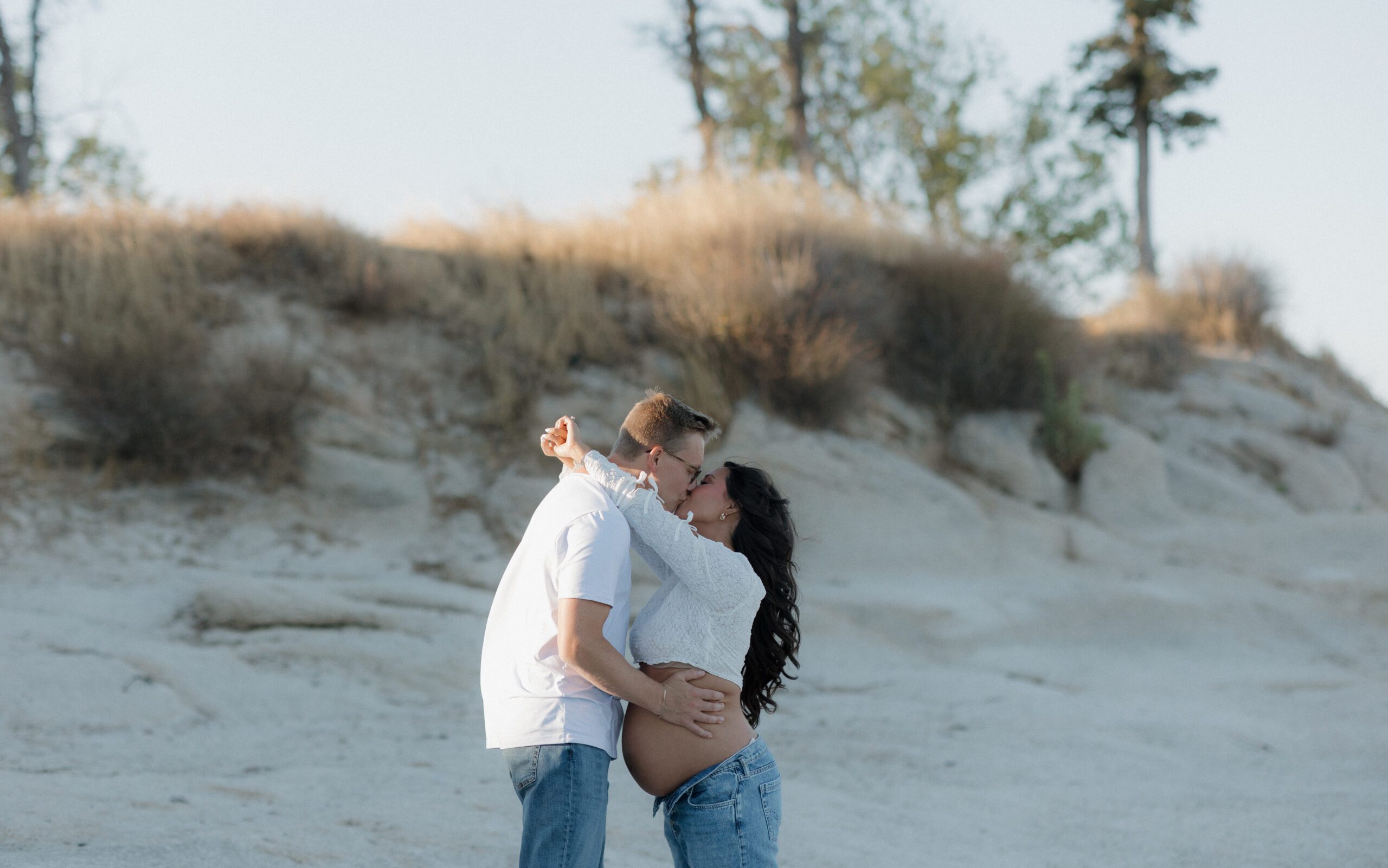 A couple kissing with their baby bump in the middle of them 