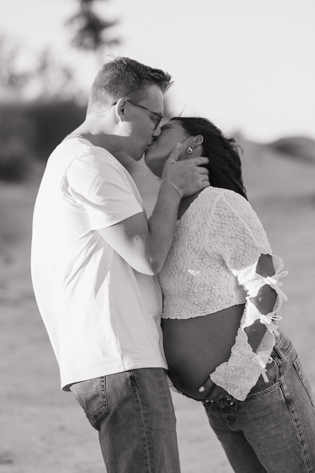A black and white photo of a mother and father kissing during their maternity photoshoot