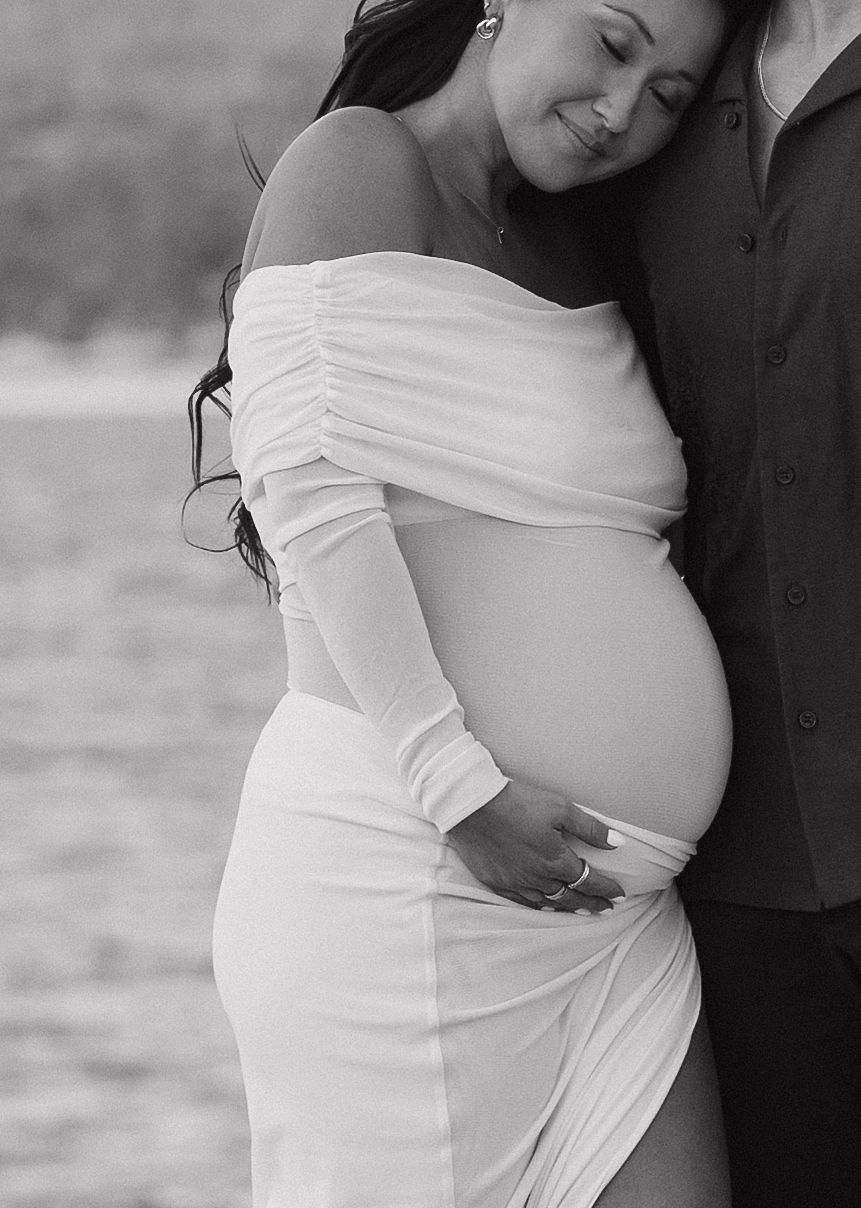 Black and white photo of woman holding her baby bump