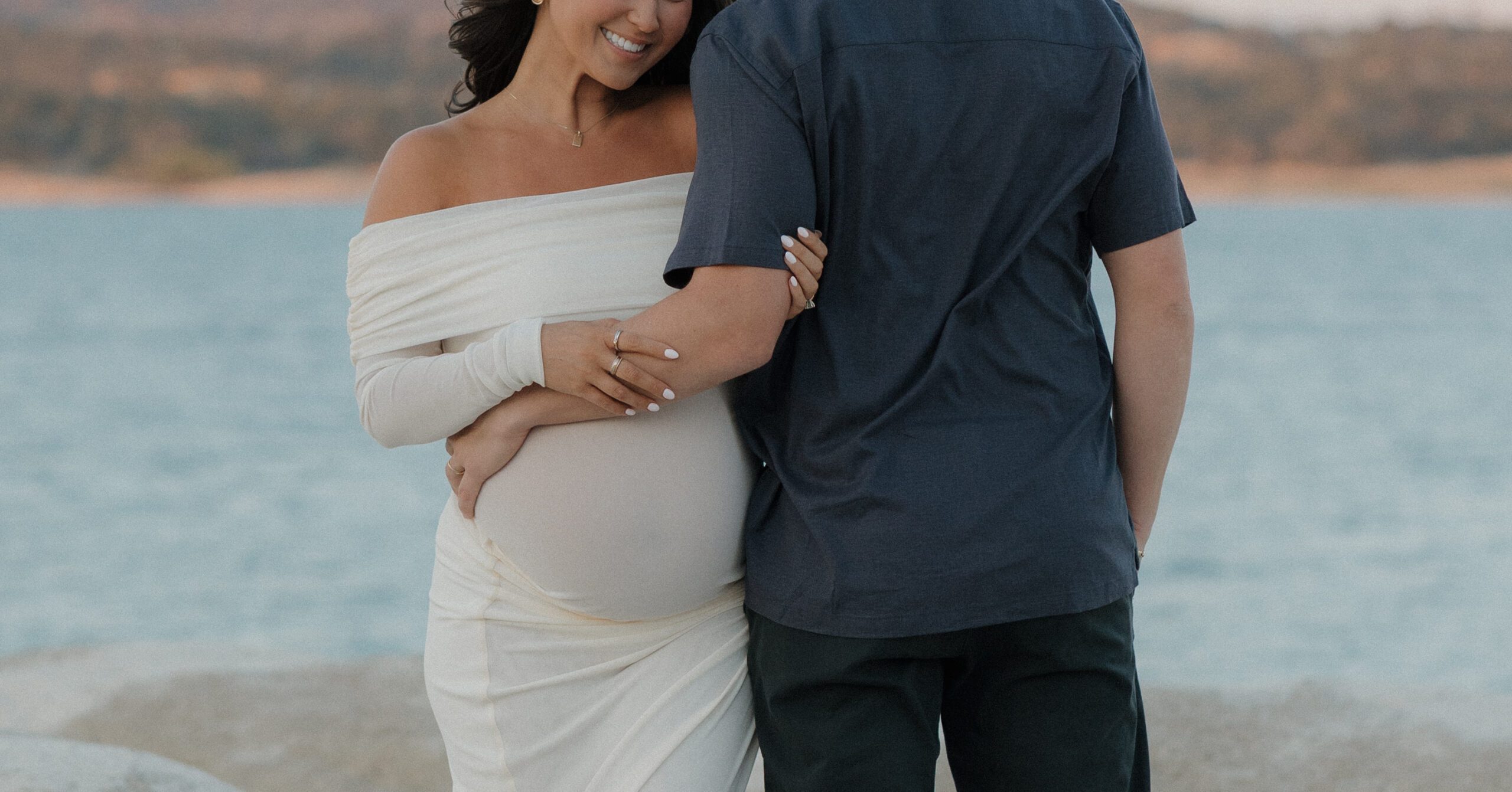 Maternity photo of woman hugging man's arm, who is turned away from the camera