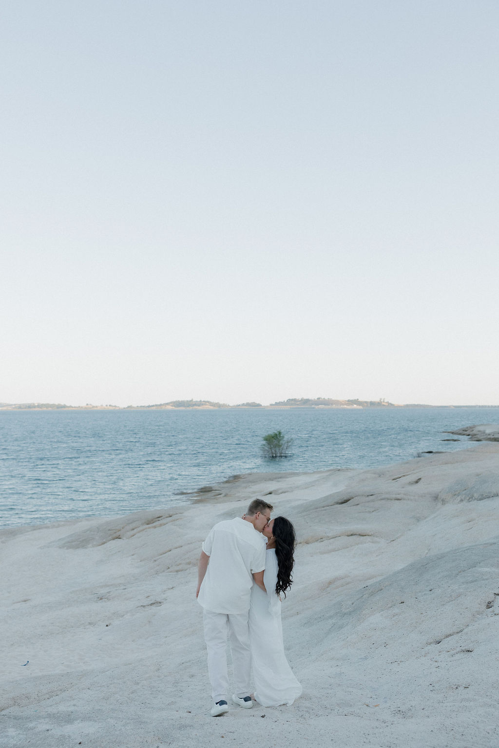 A couple kissing in front of a lake during their maternity photo session