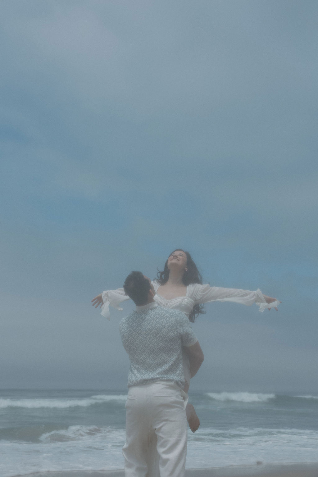 A film-inspired engagement photo with a woman being lifted and spun around by her fiancé 