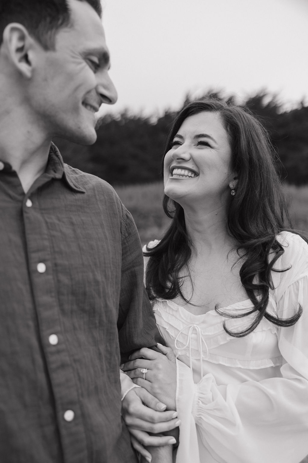 Woman smiling at her fiancé showing off her engagement ring as an engagement photoshoot pose