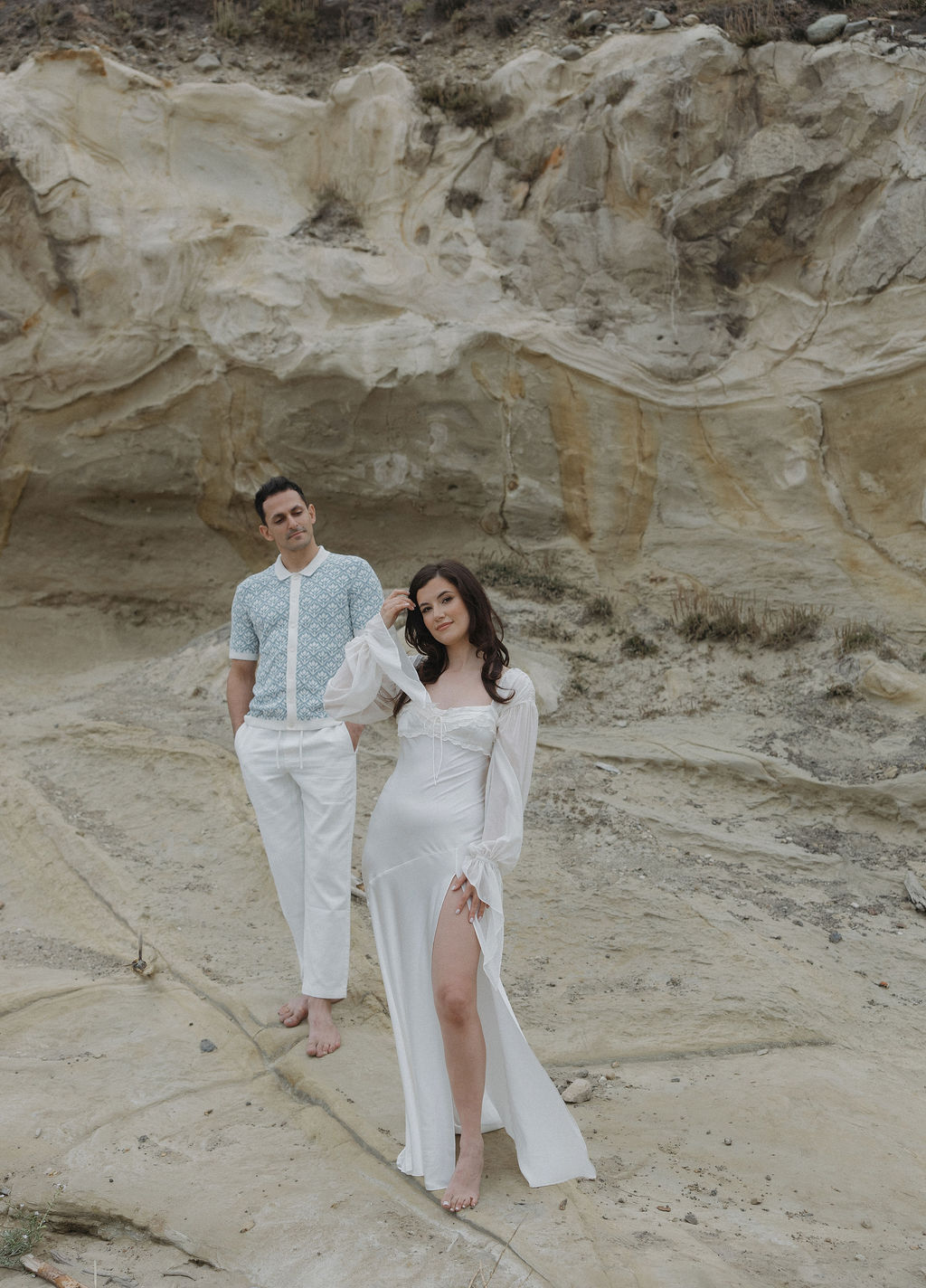 A man standing behind his fiancee who is posing for a picture