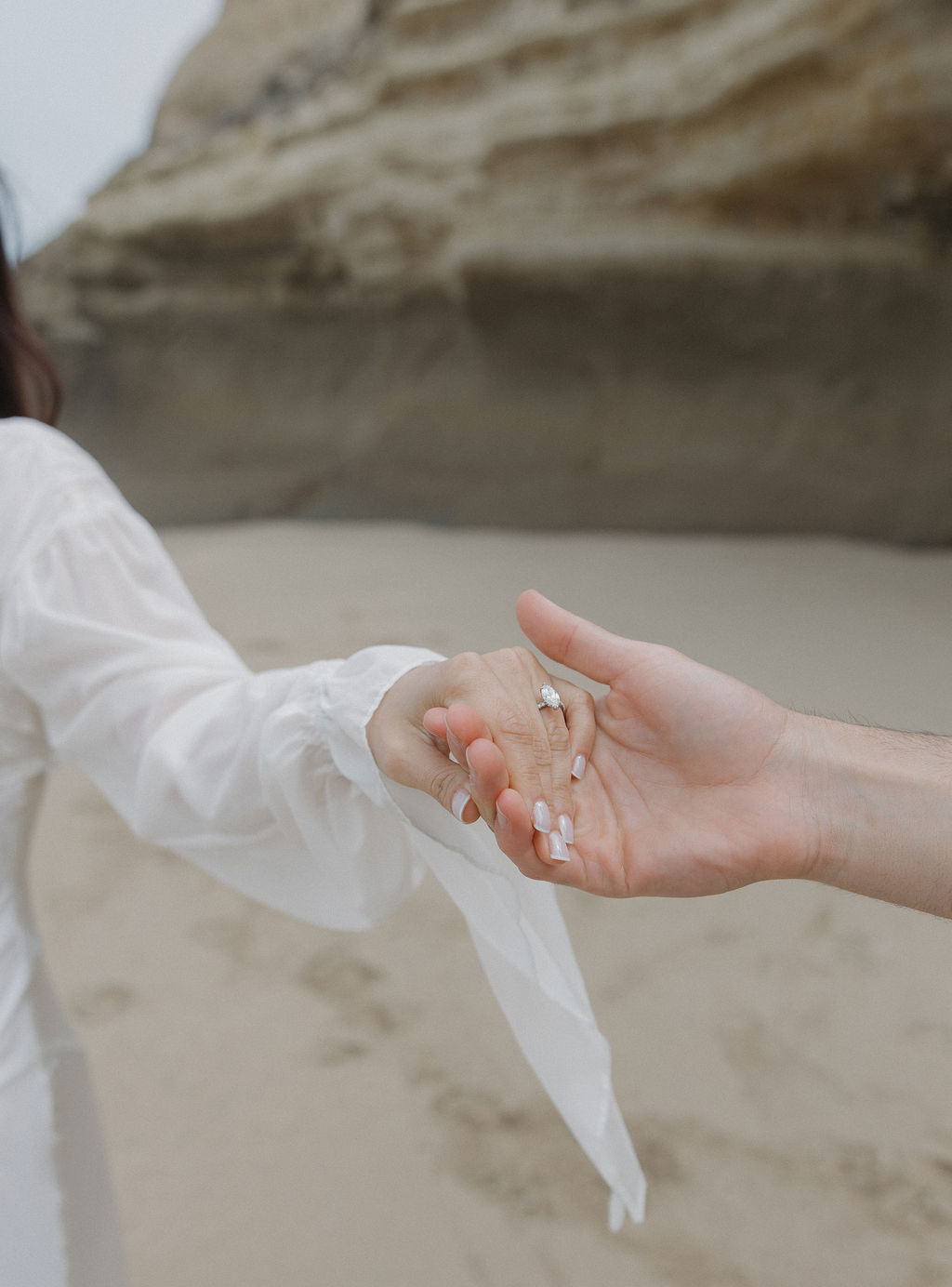 Engagement photo of man holding woman's hand, showing off her ring