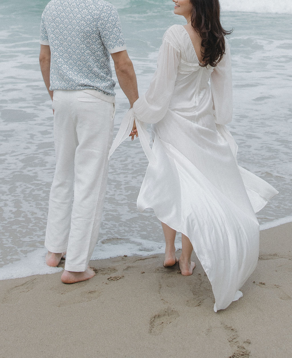 Couple walking into the ocean during their beach engagement photos