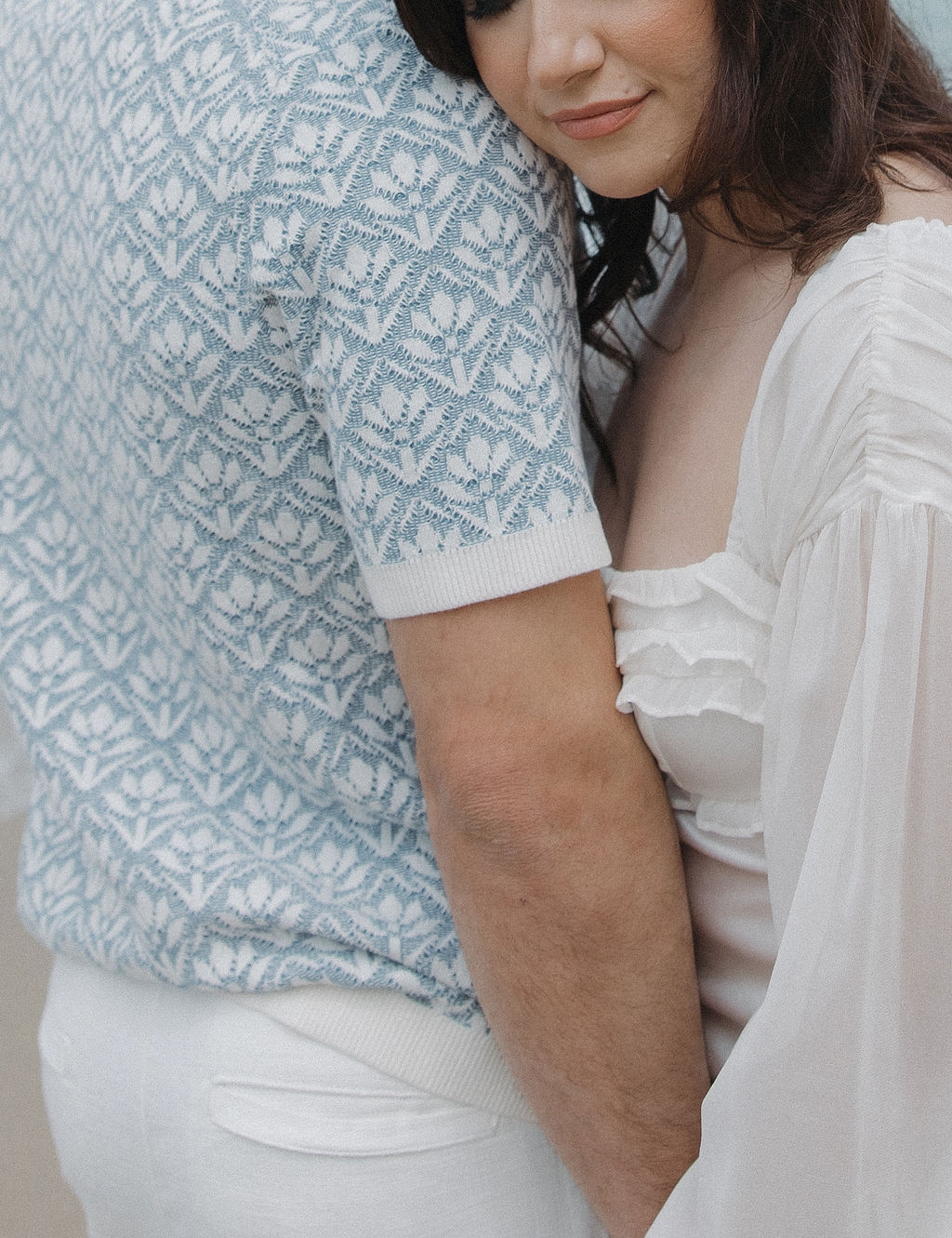 An up close photo of a woman resting her head on her fiancé's shoulder 