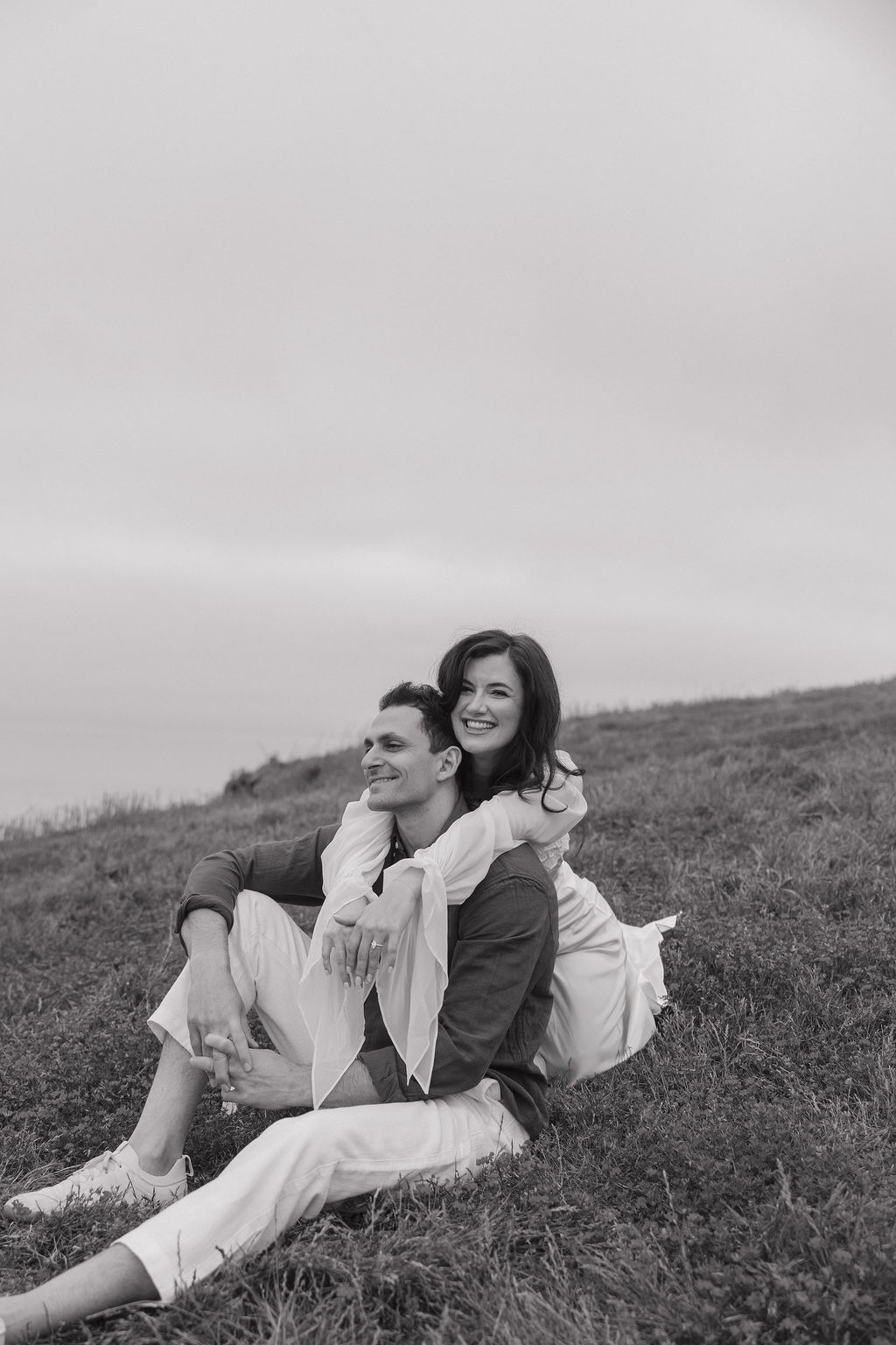 A black and white photo of a couple sitting in a field